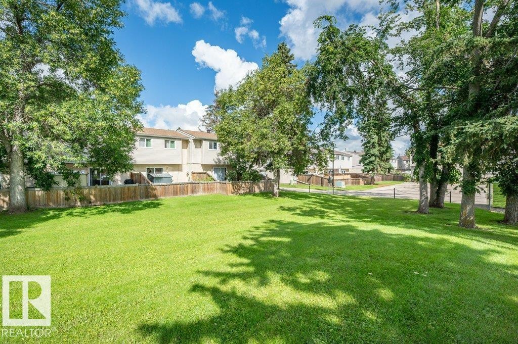 Expansive green space featuring mature trees and a wooden privacy fence - #138 5231 51 St, Bon Accord, AB - Outdoor
