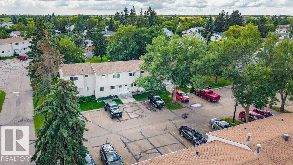 Two-story residential building with light-colored siding, a brown shingle roof, and multiple windows - #138 5231 51 St, Bon Accord, AB - Outdoor With View