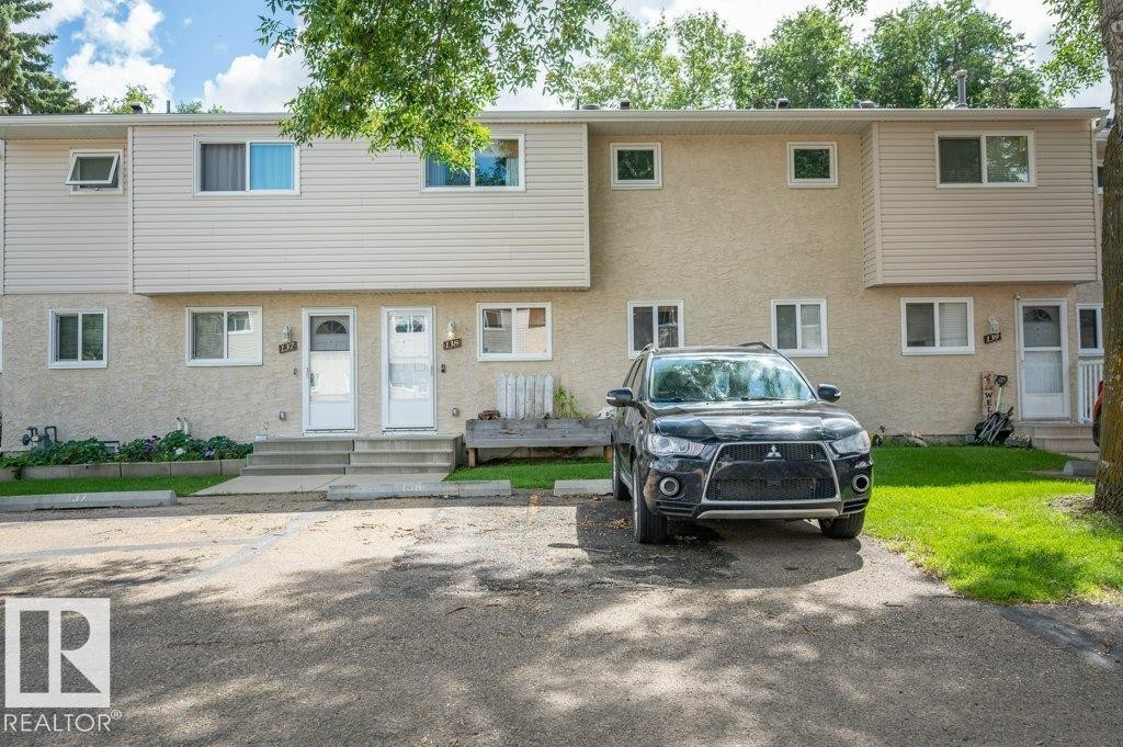 Two-story exterior with light-colored siding and stucco, featuring multiple windows. 2 parking stalls for the unit - #138 5231 51 St, Bon Accord, AB - Outdoor