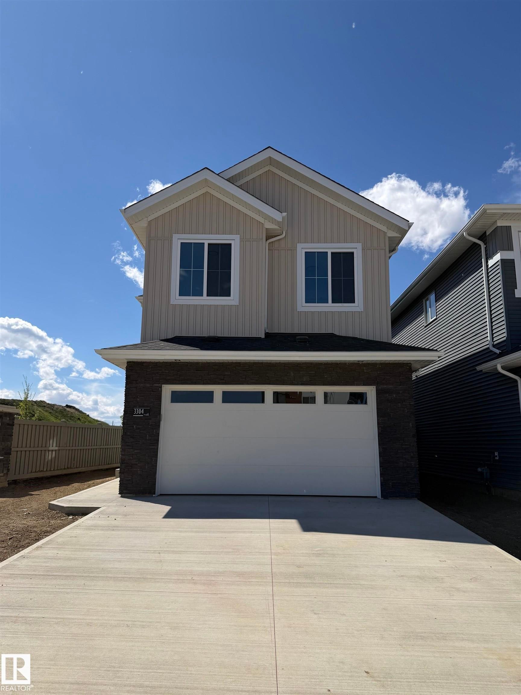 Contemporary residence with a concrete driveway, attached garage, and stone facade accents - 3304 Chickadee Drive Nw, Edmonton, AB - Outdoor