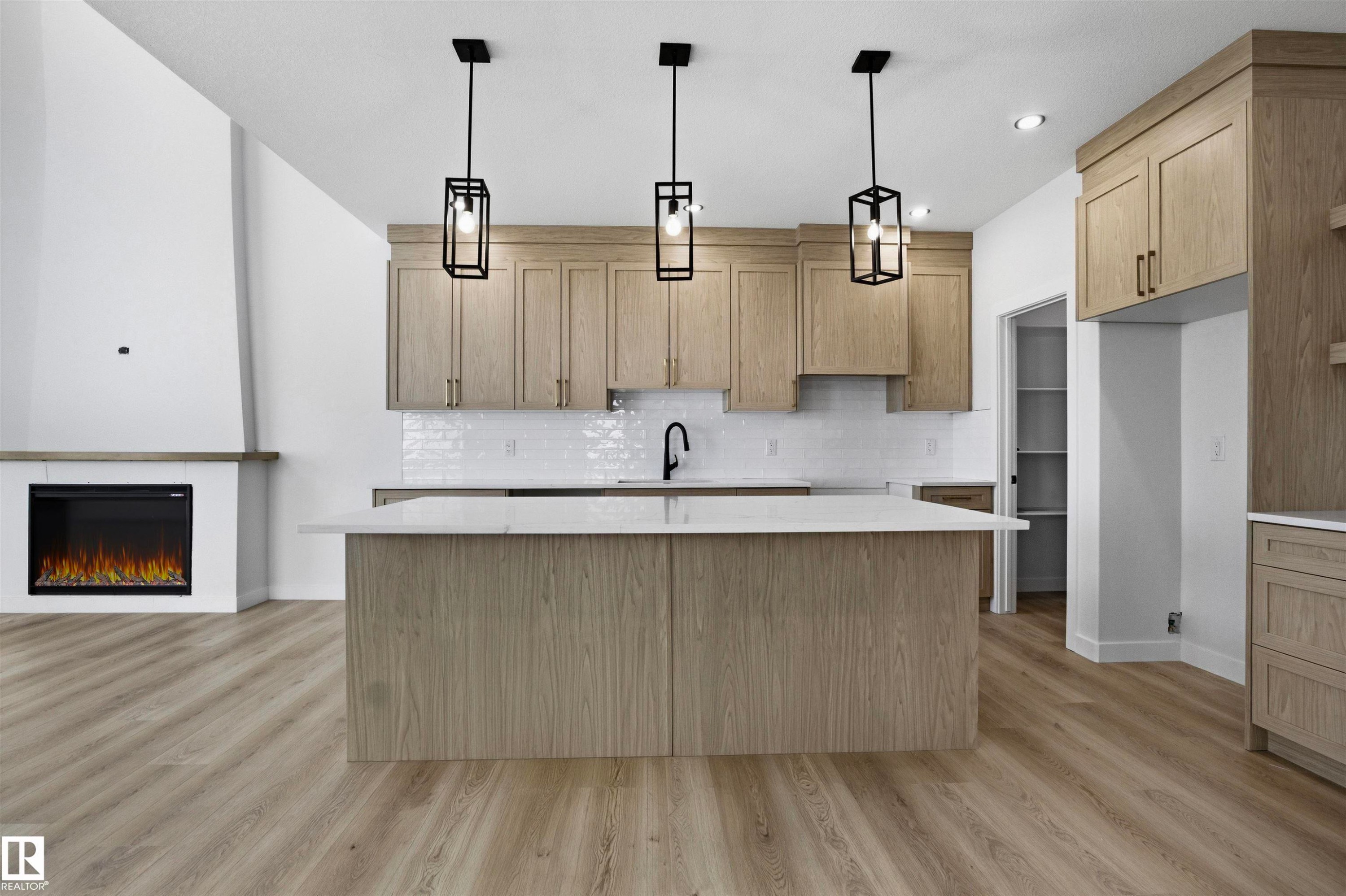 Contemporary kitchen featuring wood-finish cabinetry, a white subway tile backsplash, and a large island with a light-toned countertop - 3304 Chickadee Drive Nw, Edmonton, AB - Indoor Photo Showing Kitchen With Upgraded Kitchen