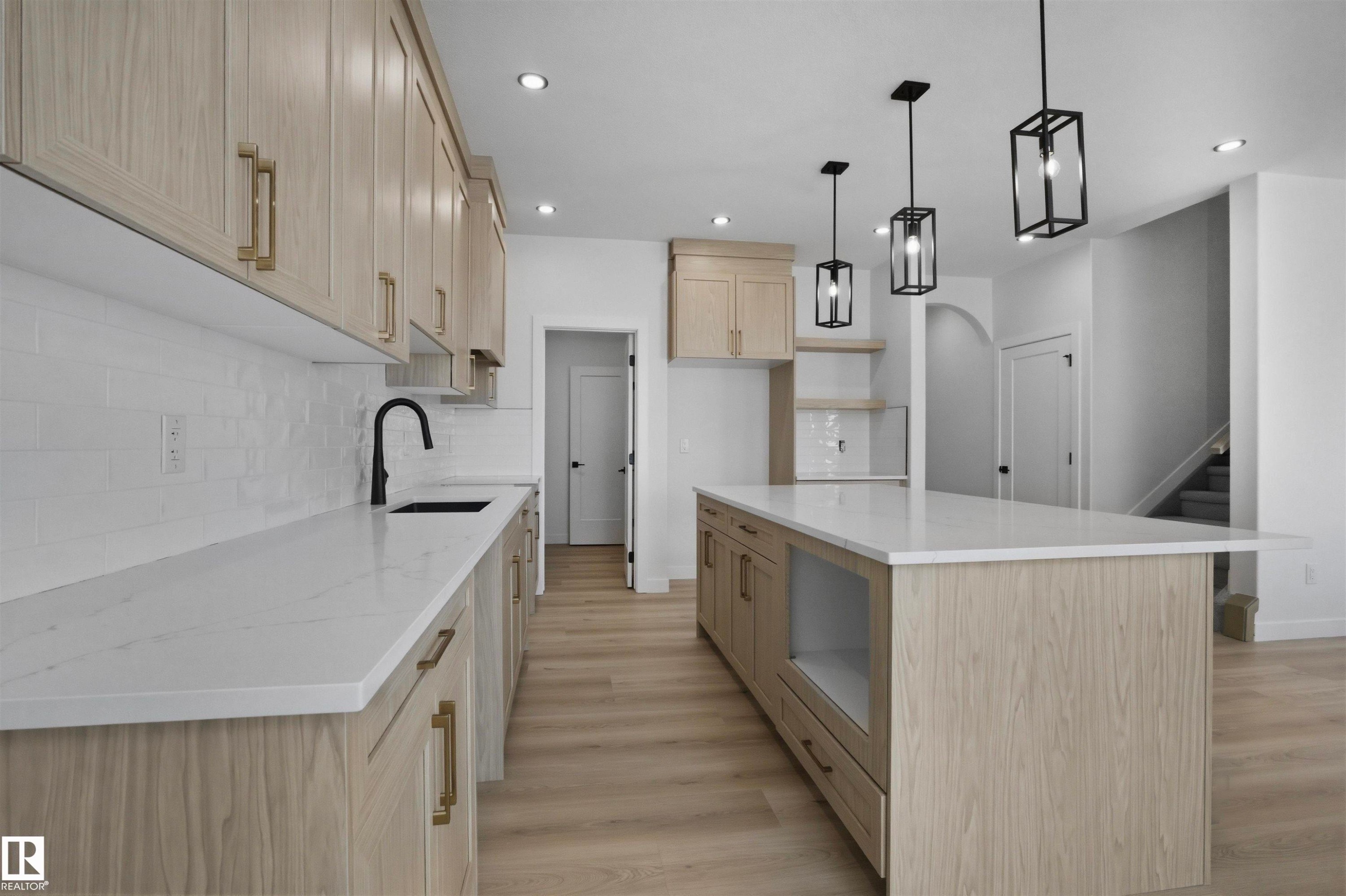 Spacious kitchen featuring an expansive island, light wood-finish cabinetry, white countertops, recessed lighting, and modern pendant light fixtures - 3304 Chickadee Drive Nw, Edmonton, AB - Indoor Photo Showing Kitchen With Upgraded Kitchen
