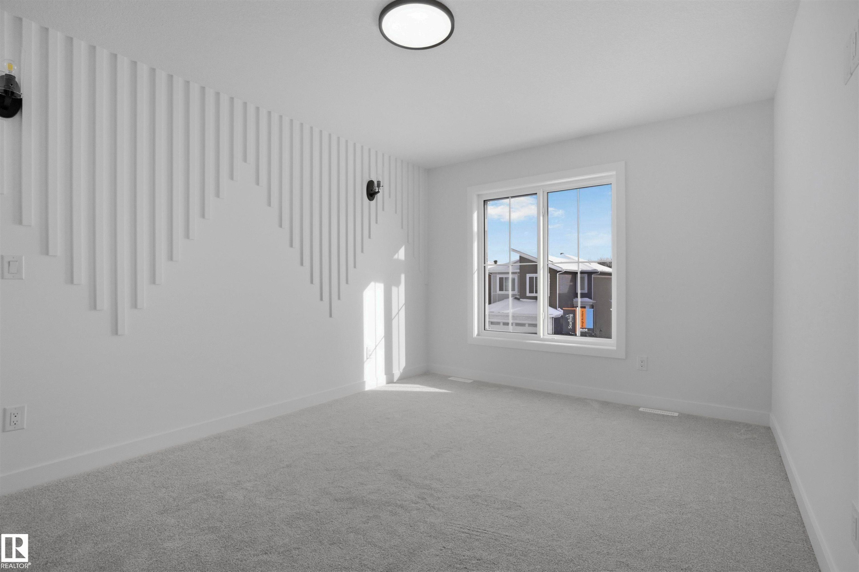 Textured accent wall, ceiling-mounted light fixture, wall-mounted light fixtures, window with white frame, gray carpet flooring - 3304 Chickadee Drive Nw, Edmonton, AB - Indoor Photo Showing Other Room