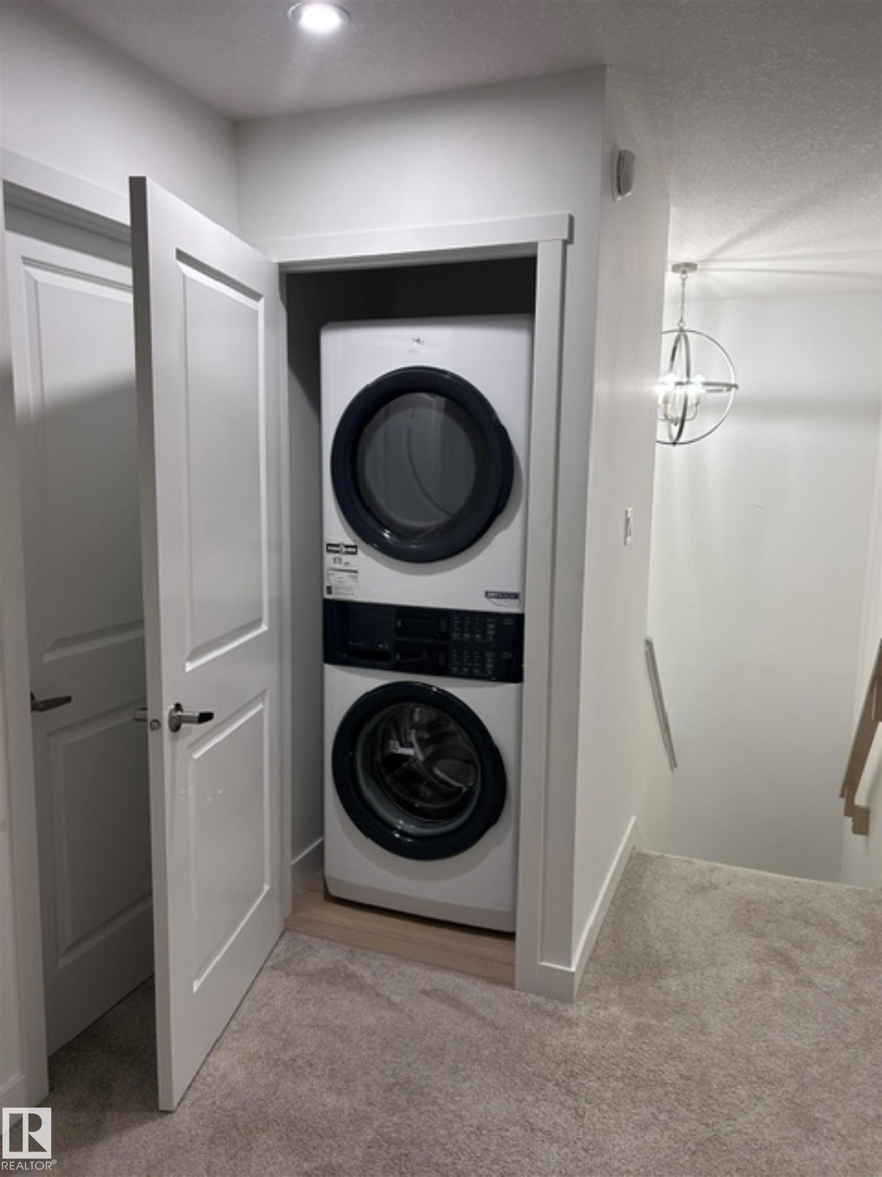 Stackable washer and dryer within a dedicated closet - 20936 16 Avenue Nw, Edmonton, AB - Indoor Photo Showing Laundry Room