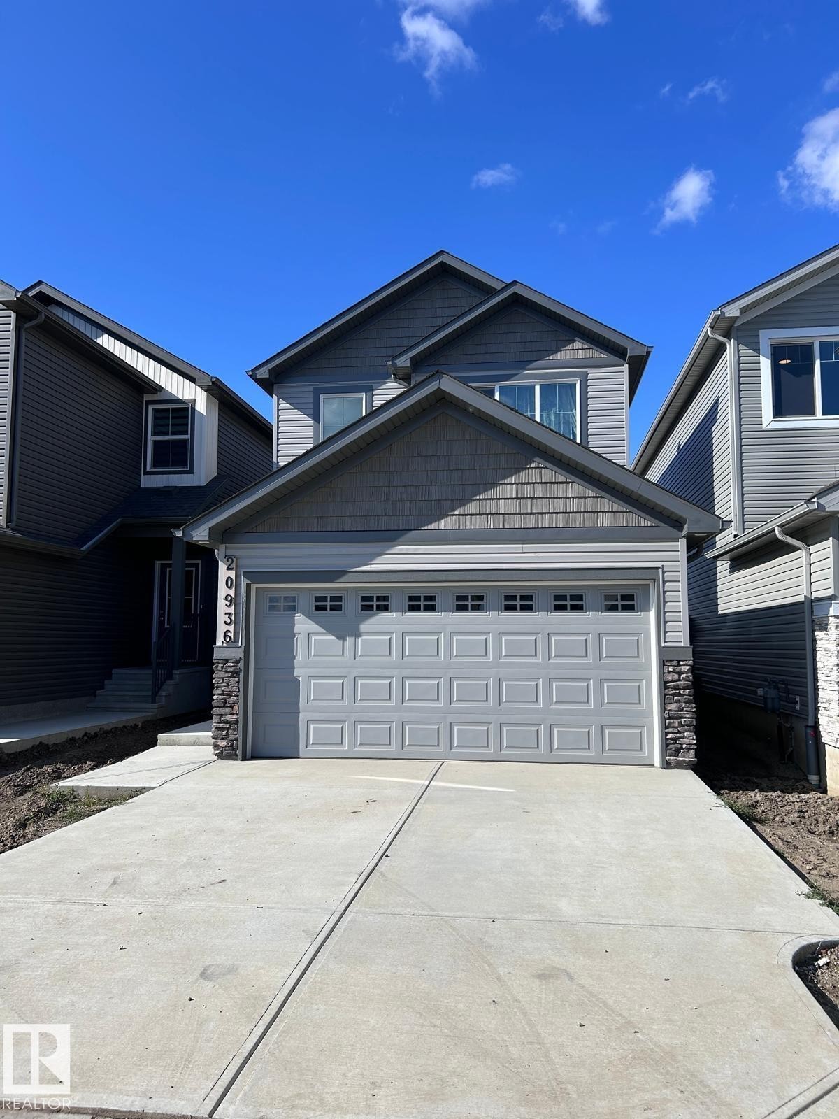 Two-story exterior with multi-toned siding, stone accents, and a front-facing garage - 20936 16 Avenue Nw, Edmonton, AB - Outdoor