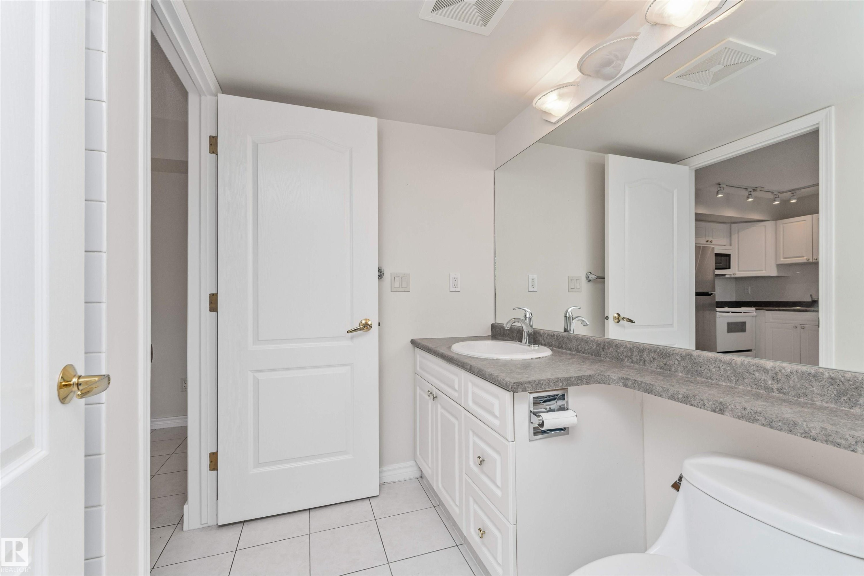 White vanity with a single basin, grey flecked countertop, and large wall-mounted mirror - #1101 10909 103 Av Nw, Edmonton, AB - Indoor Photo Showing Bathroom