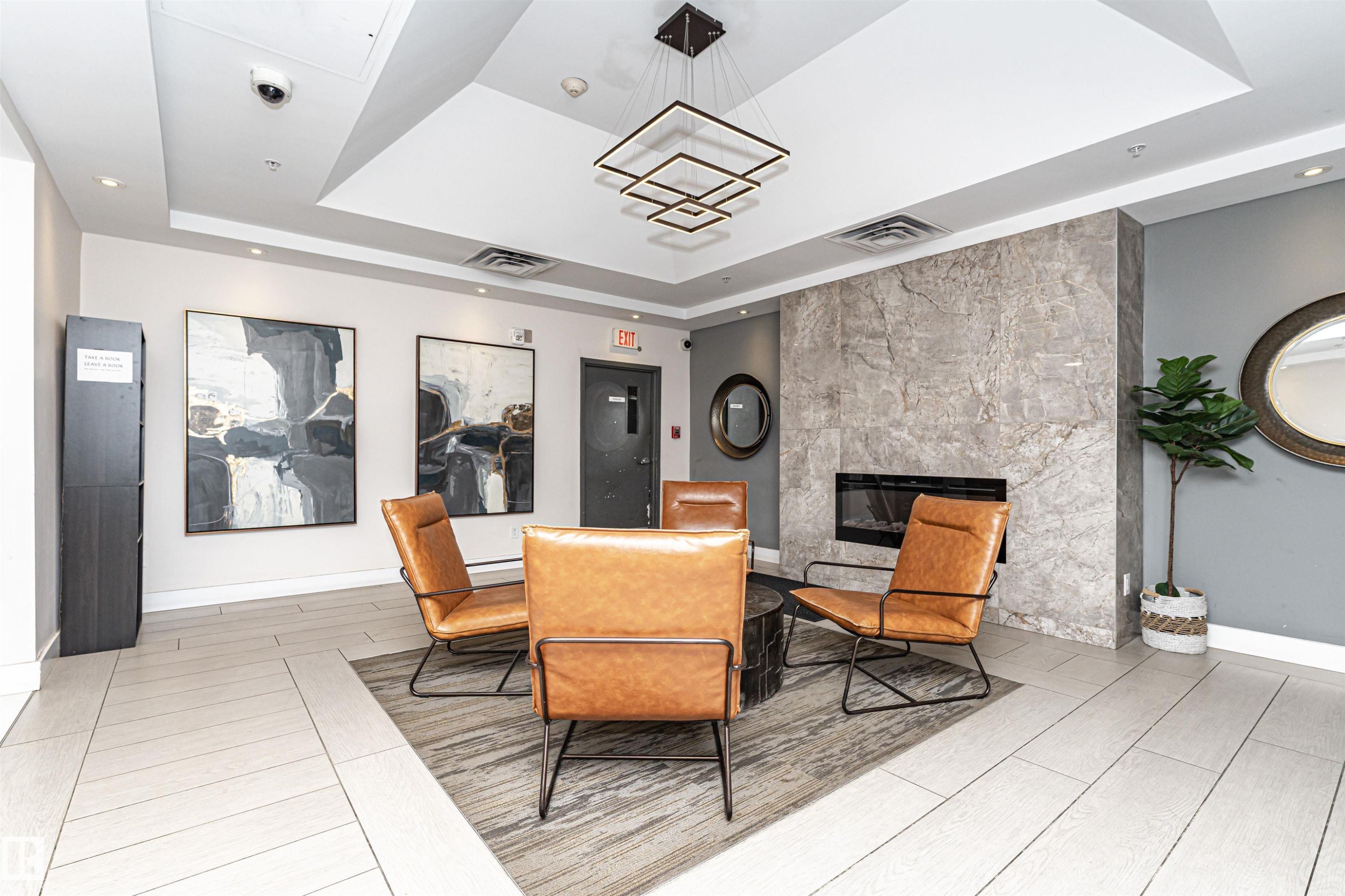 Modern lobby featuring polished light-finish flooring, coffered ceiling with recessed lighting, and a neutral color palette - #1101 10909 103 Av Nw, Edmonton, AB - Indoor With Fireplace
