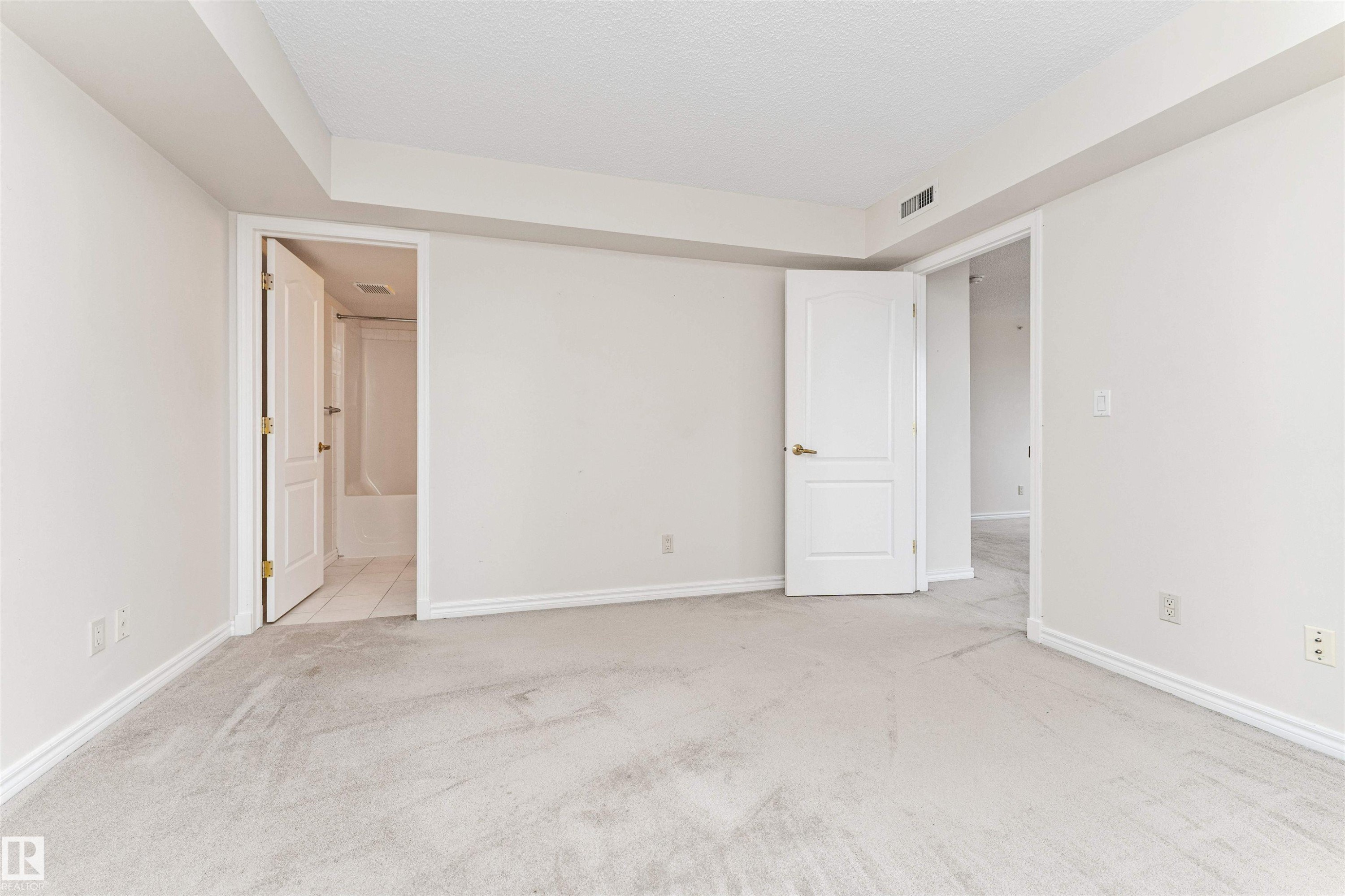 Light-toned wall finishes, neutral carpet flooring, white trim, and a white interior door with brass hardware - #1101 10909 103 Av Nw, Edmonton, AB - Indoor Photo Showing Other Room