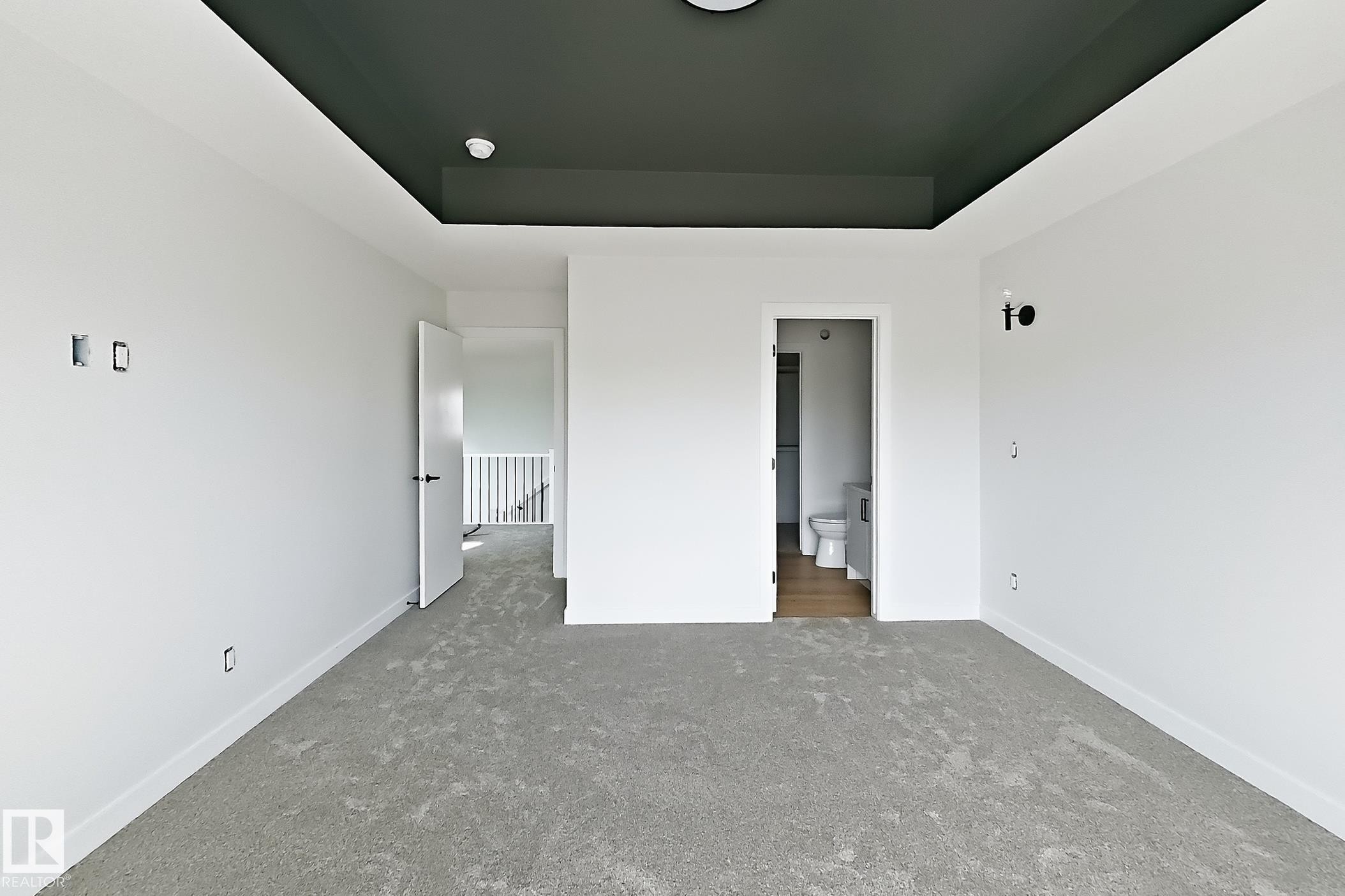 Neutral tone paint, recessed ceiling with accent color, light gray carpeting, contemporary white doors, and wall-mounted light fixtures - 13118 186 Avenue Nw, Edmonton, AB - Indoor Photo Showing Other Room