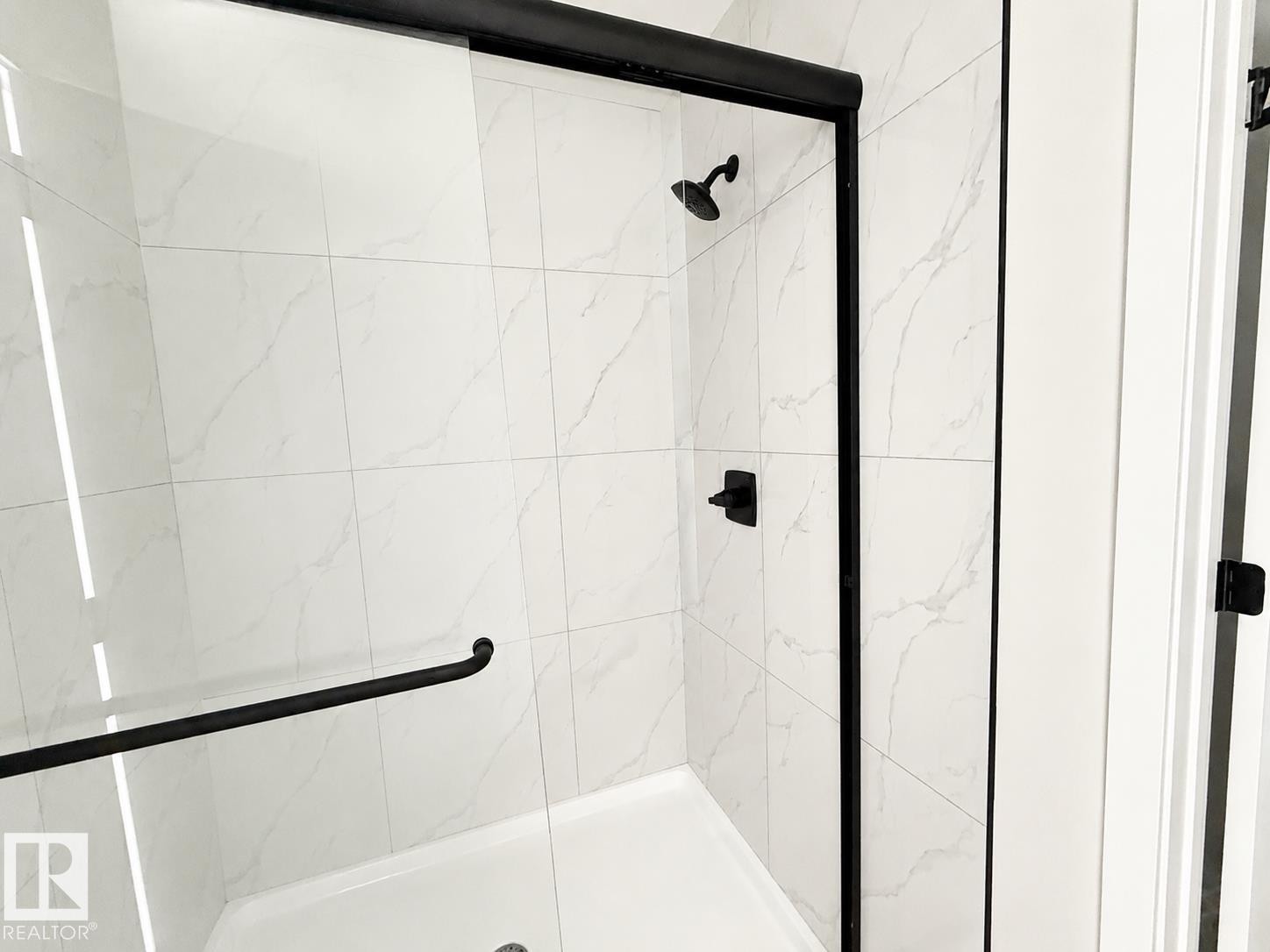 Glass-enclosed shower with matte black hardware, a shower head, and a lever control - 13118 186 Avenue Nw, Edmonton, AB - Indoor Photo Showing Bathroom