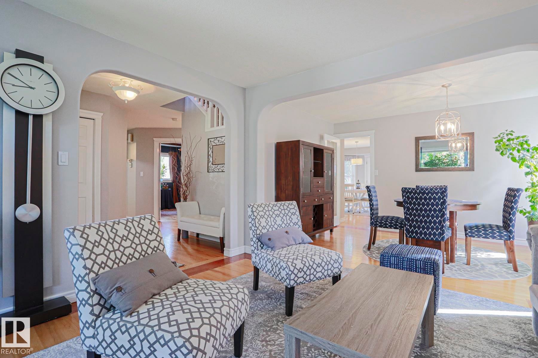 Light-colored walls, wood-finish flooring, arched doorways, white trim, and a contemporary chandelier - 12 Douziech Close, St. Albert, AB - Indoor Photo Showing Other Room