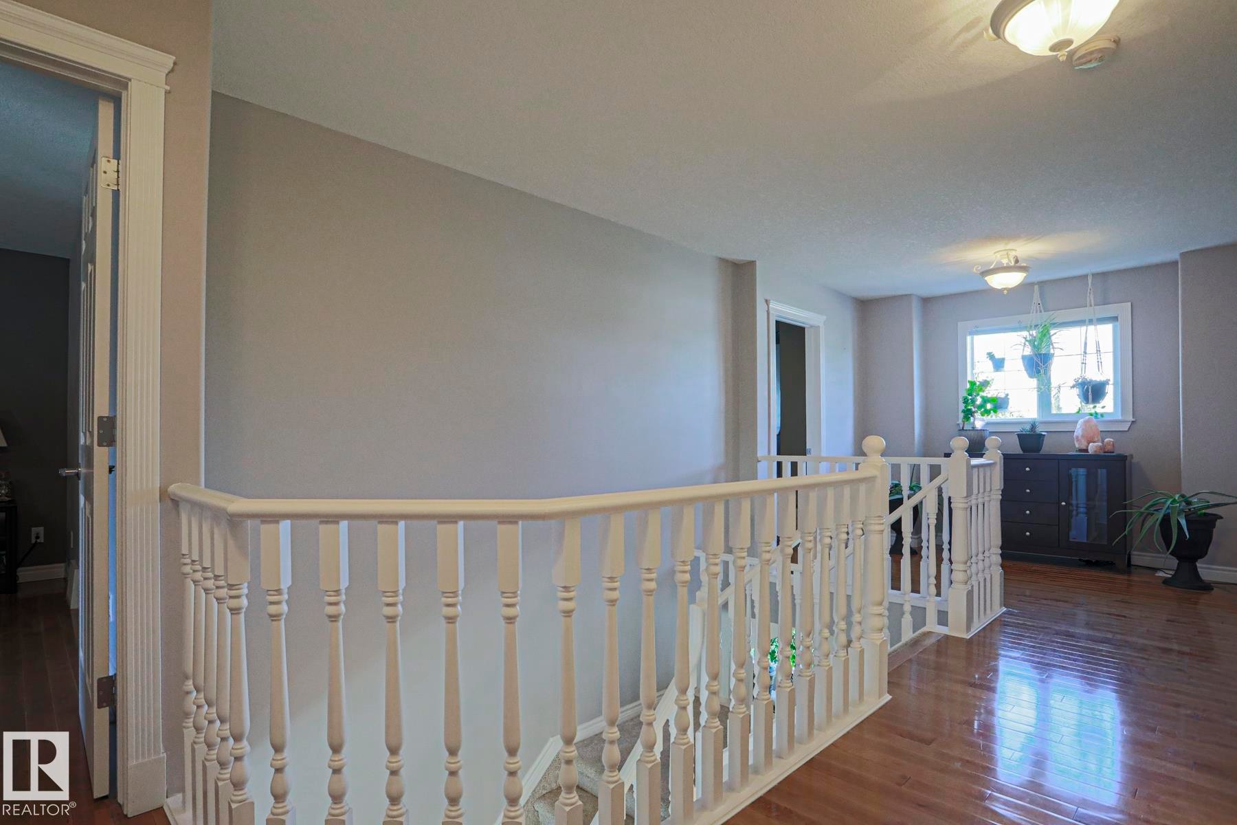 Hardwood flooring, painted banister, recessed lighting, and a large window - 12 Douziech Close, St. Albert, AB - Indoor Photo Showing Other Room