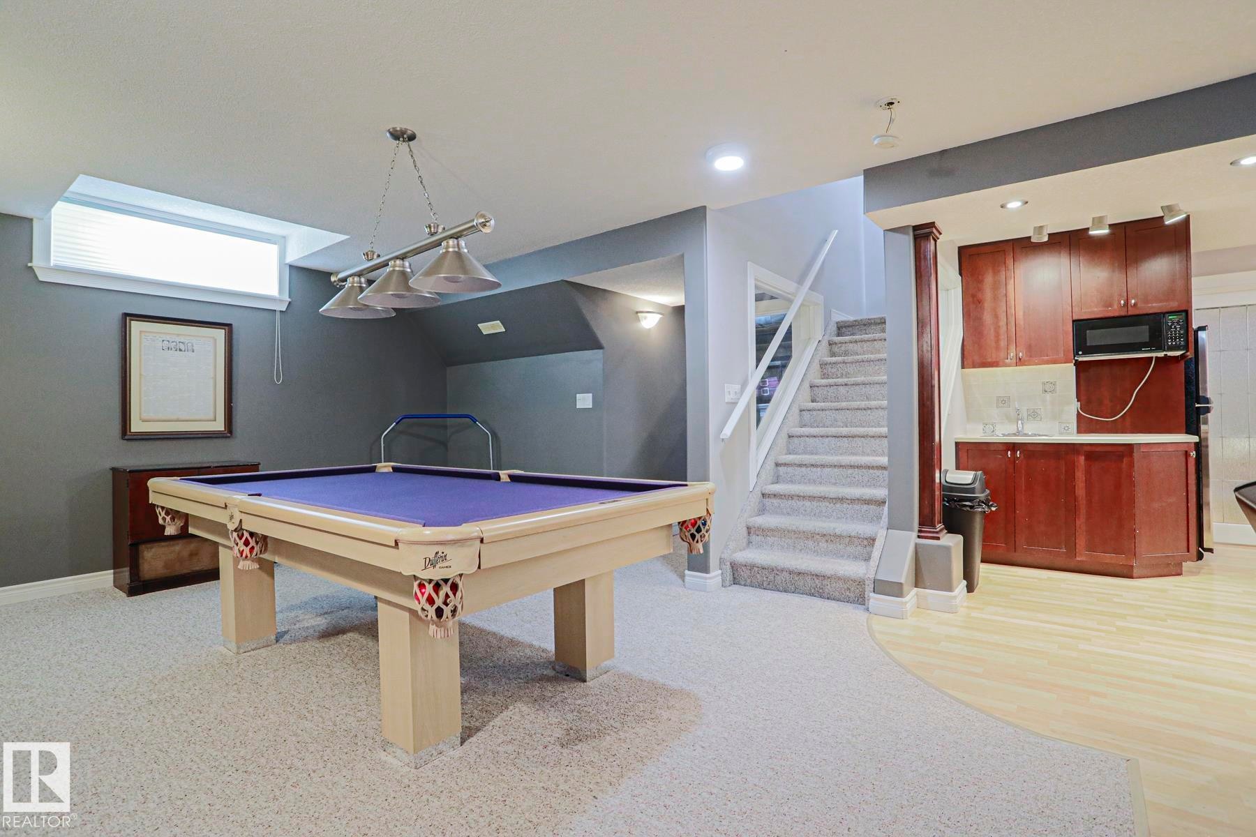 Finished basement with mixed flooring, built-in wet bar, and carpeted stairs with white railing - 12 Douziech Close, St. Albert, AB - Indoor Photo Showing Other Room