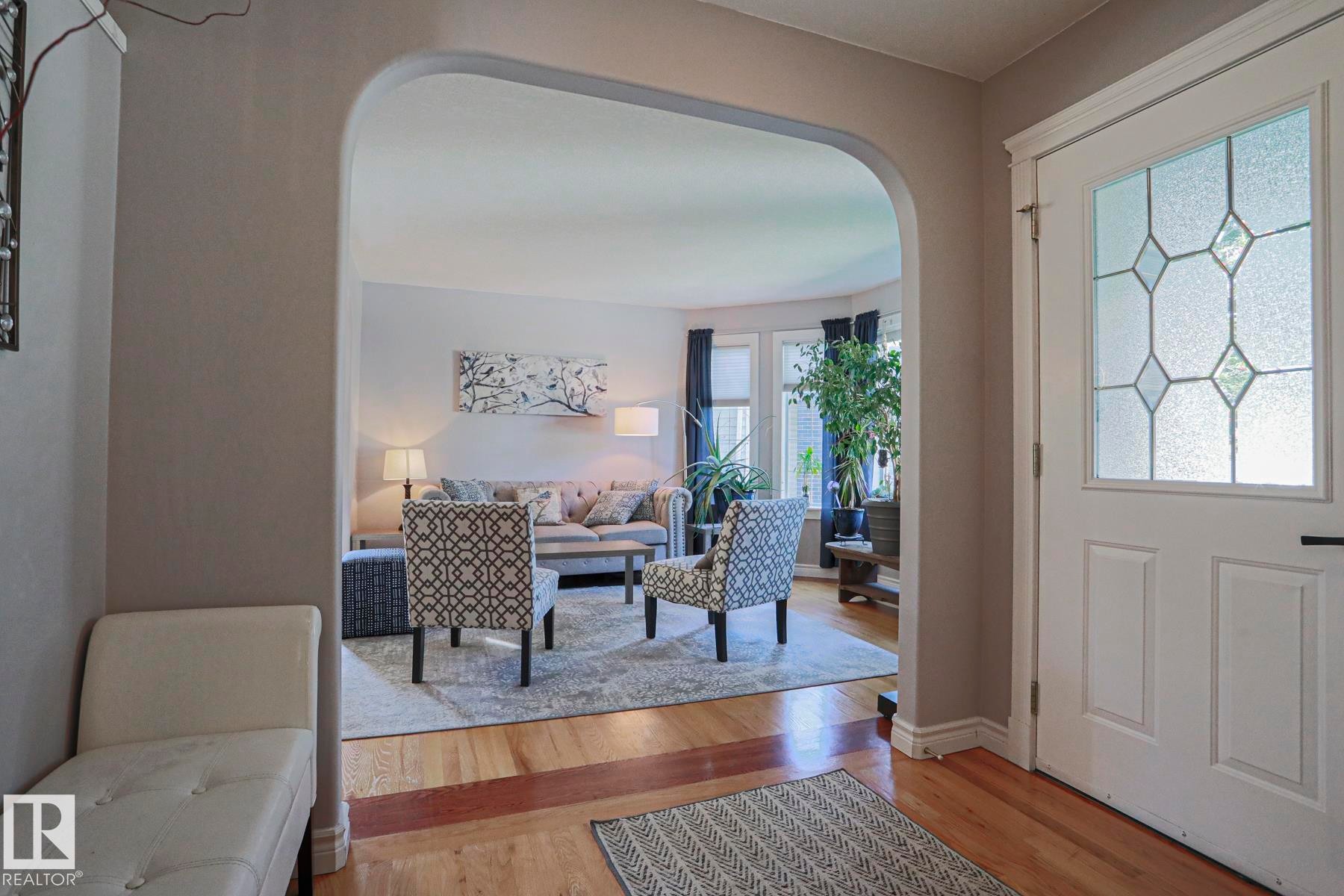 Entryway featuring an arched opening, wood-finish flooring, and a decorative frosted glass paneled door - 12 Douziech Close, St. Albert, AB - Indoor