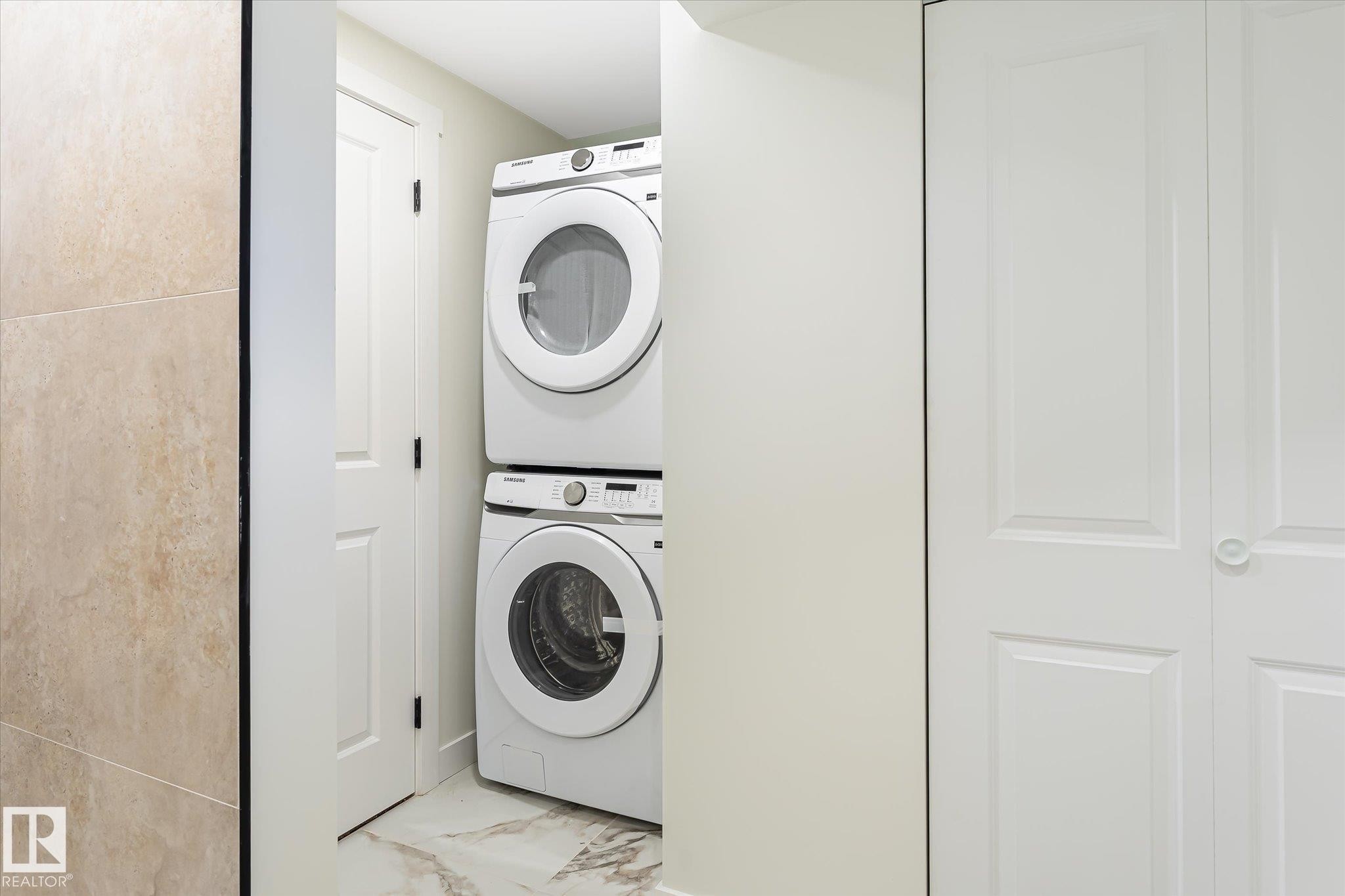 Stackable laundry appliances, panel doors, and tiled flooring - 18307 66 Avenue Nw, Edmonton, AB - Indoor Photo Showing Laundry Room