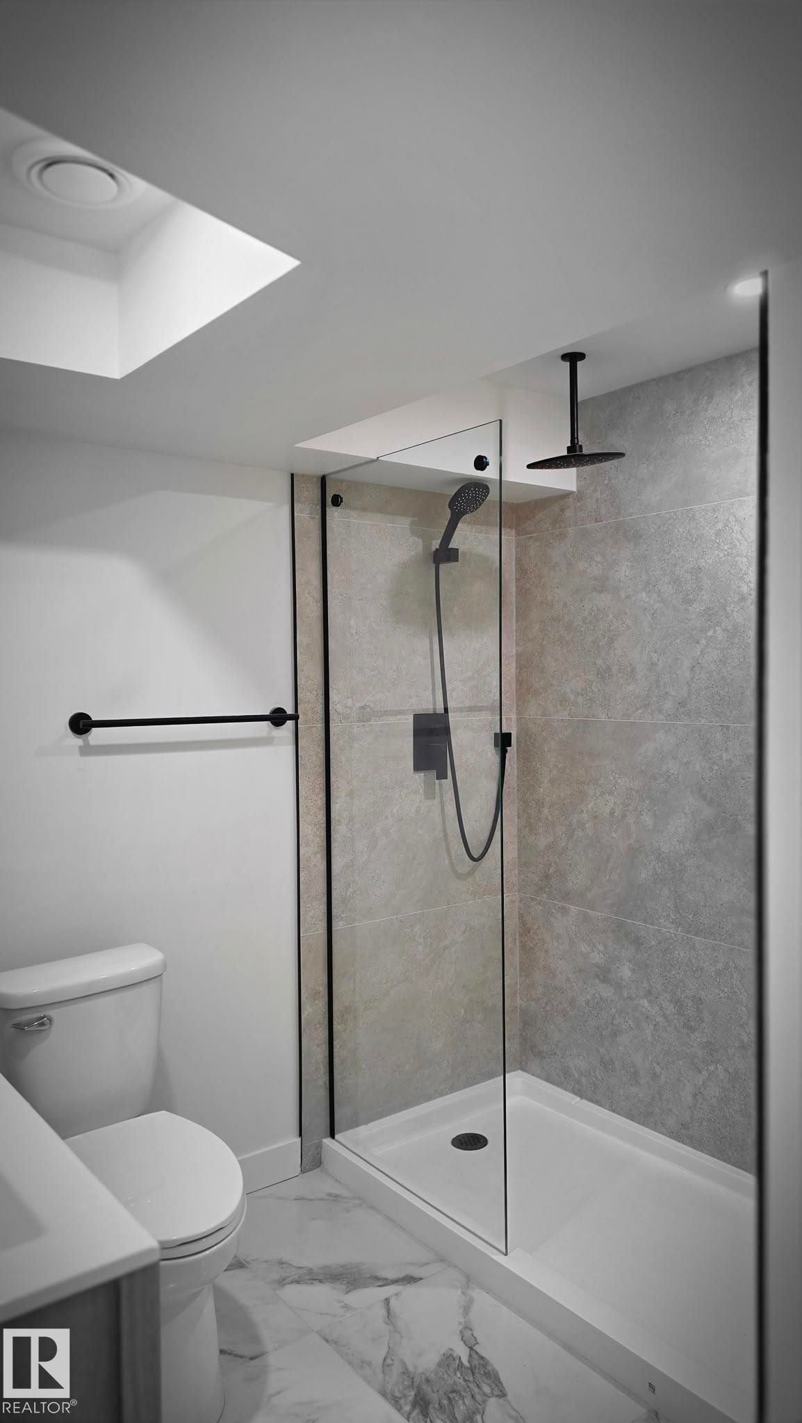Walk-in shower with a glass enclosure, black-finish fixtures, and a ceiling-mounted rainfall shower head - 18307 66 Avenue Nw, Edmonton, AB - Indoor Photo Showing Bathroom