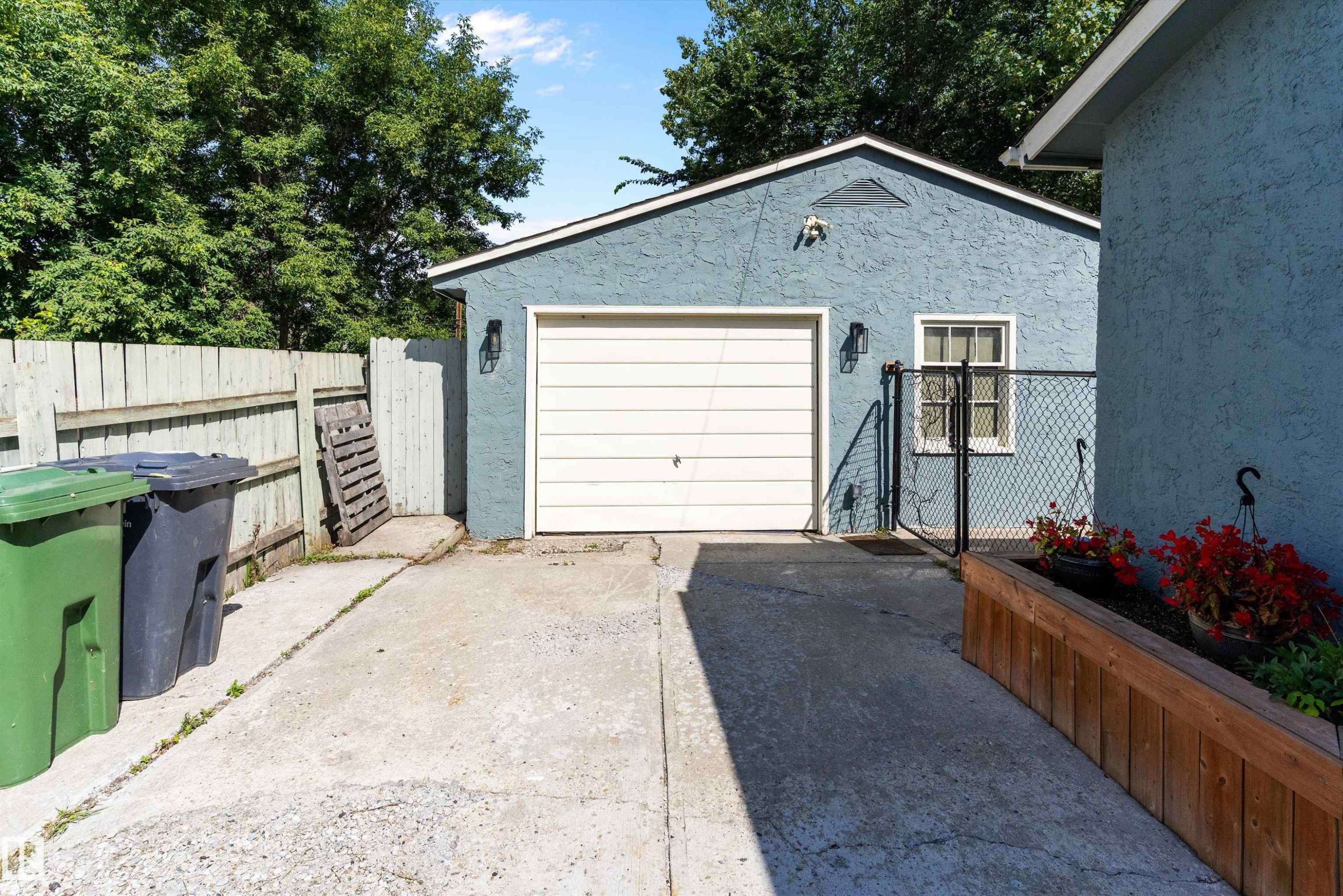 Detached garage with a paneled door, exterior wall sconces, and a side window - 5404 45 Avenue, Wetaskiwin, AB - Outdoor With Exterior