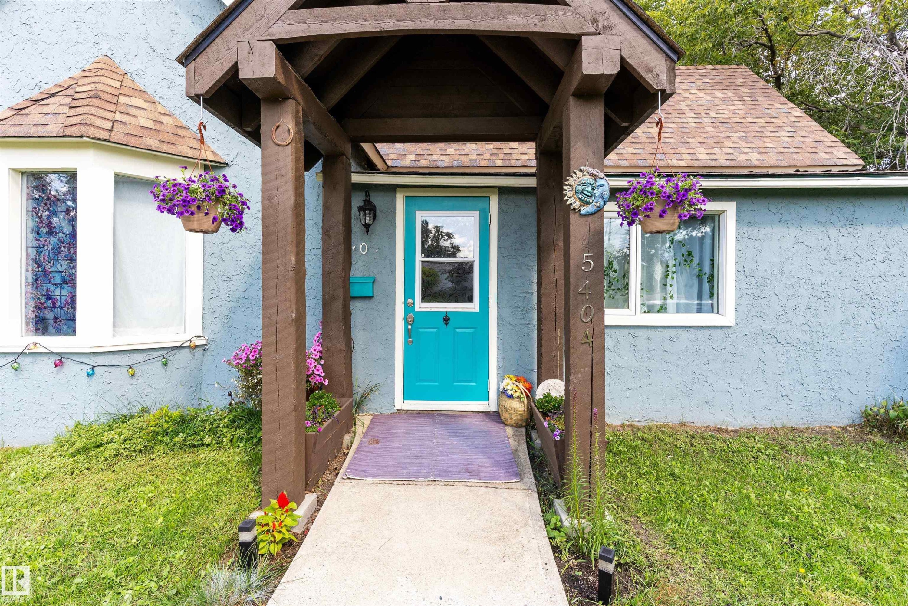 Decorative wood-beam entry porch with a vibrant teal door - 5404 45 Avenue, Wetaskiwin, AB - Outdoor
