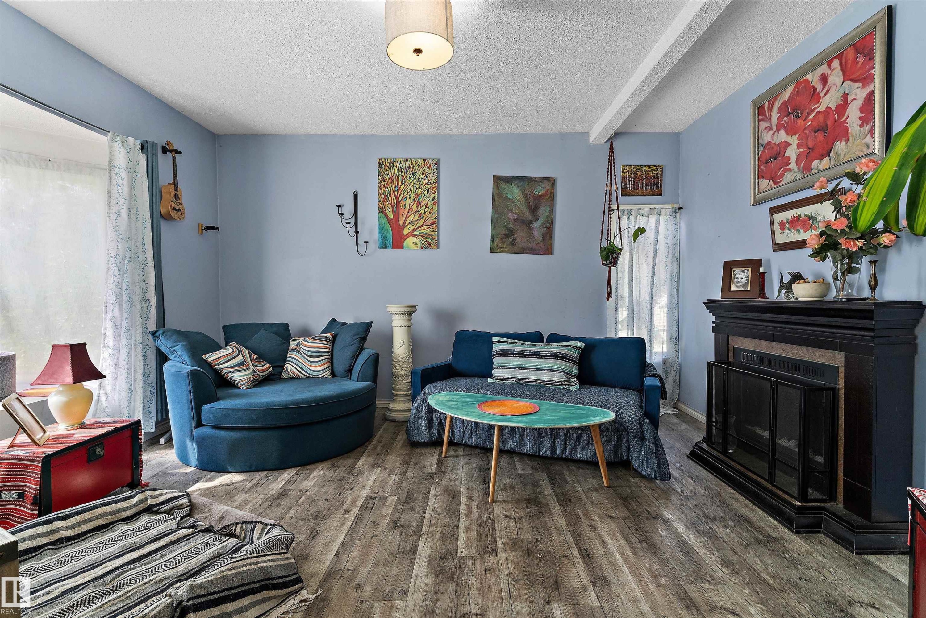 Wood-finish flooring, a ceiling-mounted light fixture, and a built-in fireplace with a dark mantel - 5404 45 Avenue, Wetaskiwin, AB - Indoor Photo Showing Living Room With Fireplace
