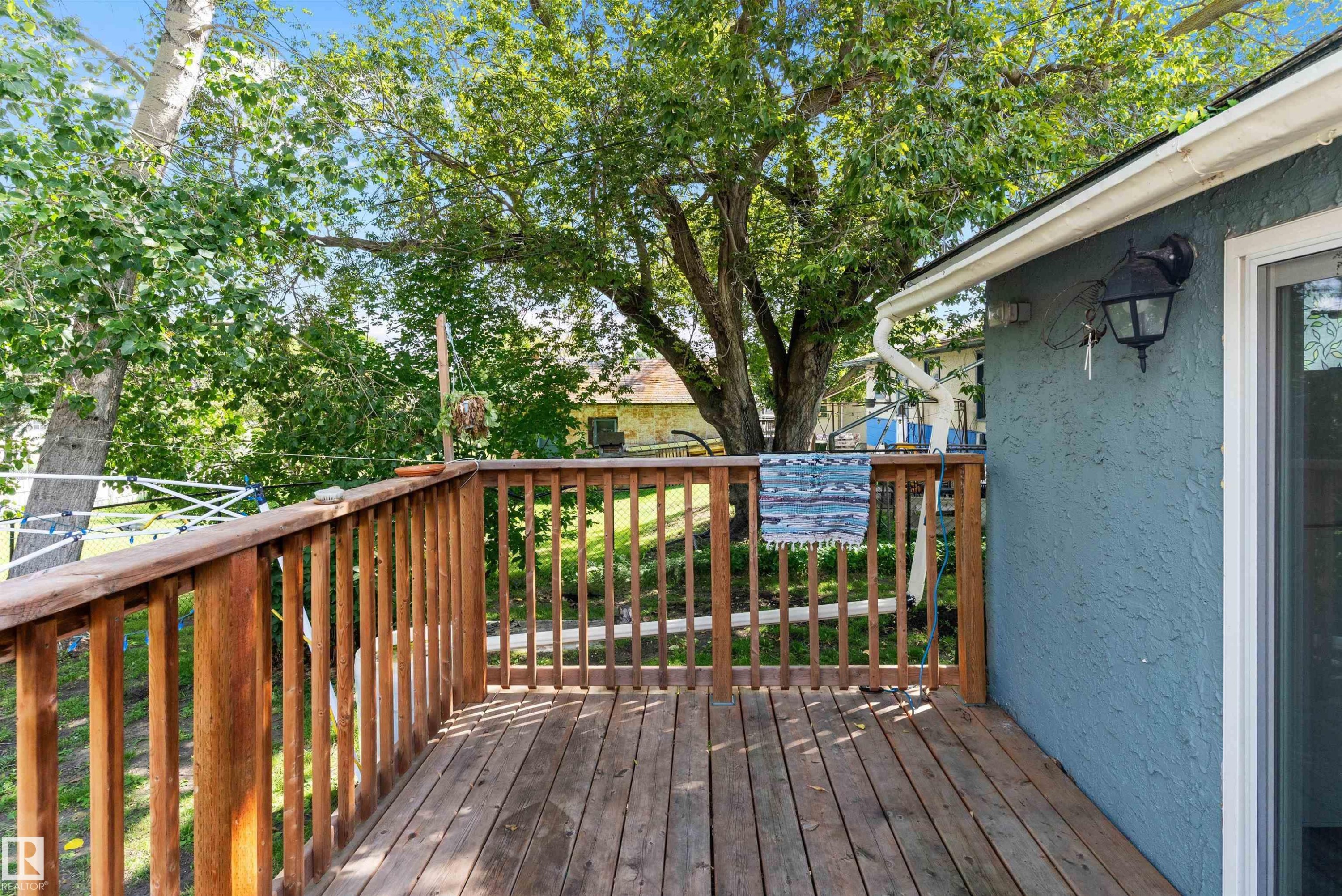 Wood deck with natural finish, featuring a sliding glass door and exterior wall sconce - 5404 45 Avenue, Wetaskiwin, AB - Outdoor With Deck Patio Veranda