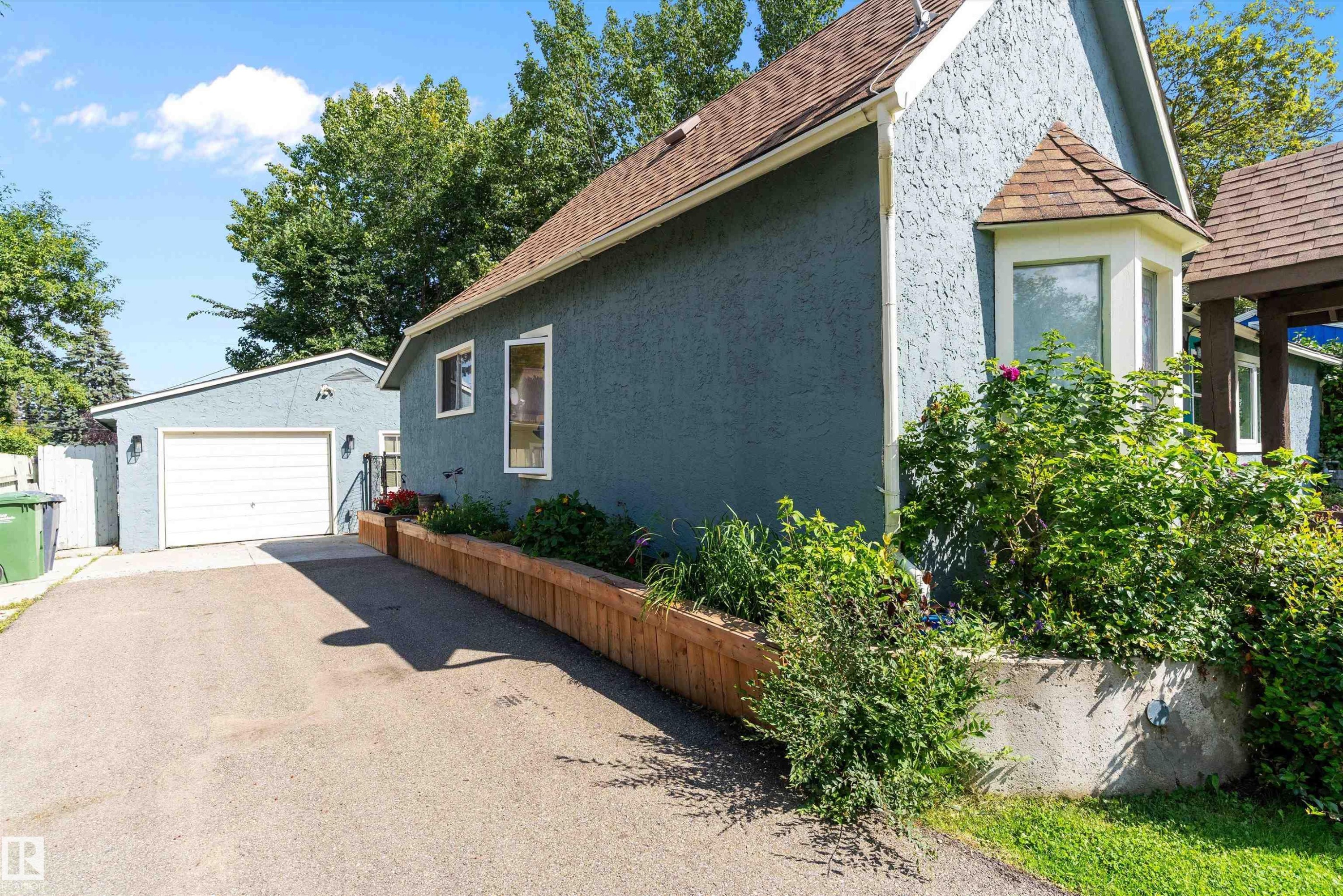 Stucco exterior with a bay window, asphalt shingle roof, and established landscaping - 5404 45 Avenue, Wetaskiwin, AB - Outdoor