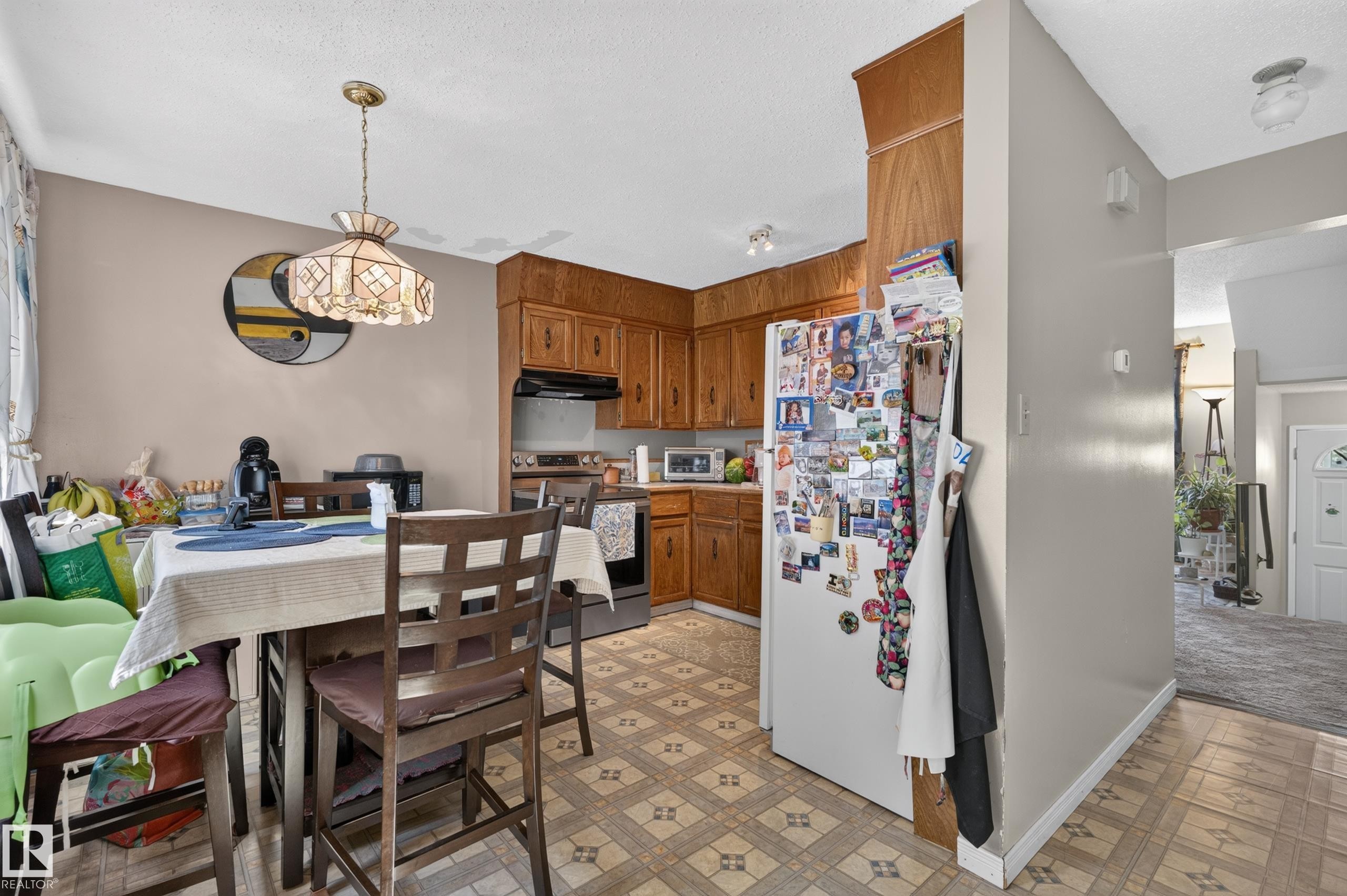 Kitchen with wood-finish cabinetry, stainless steel range, and patterned flooring - 18247 93 Avenue Nw, Edmonton, AB - Indoor Photo Showing Dining Room