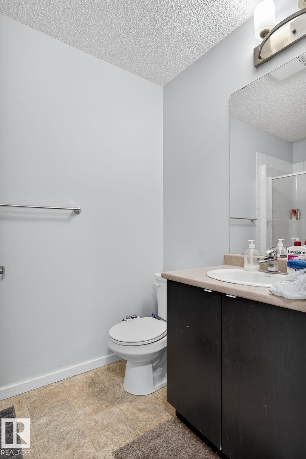 Vanity with dark wood-finish cabinetry, integrated sink, and light-toned countertop - 3353 16A Avenue Nw, Edmonton, AB - Indoor Photo Showing Bathroom