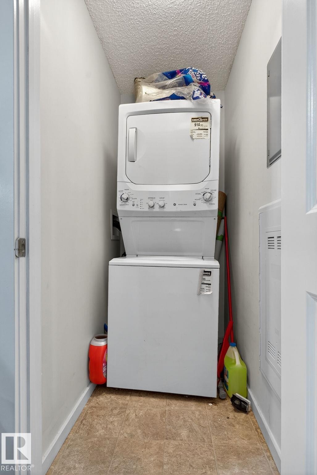 Dedicated laundry alcove featuring a stacked washer and dryer unit, and vinyl flooring - 3353 16A Avenue Nw, Edmonton, AB - Indoor Photo Showing Laundry Room
