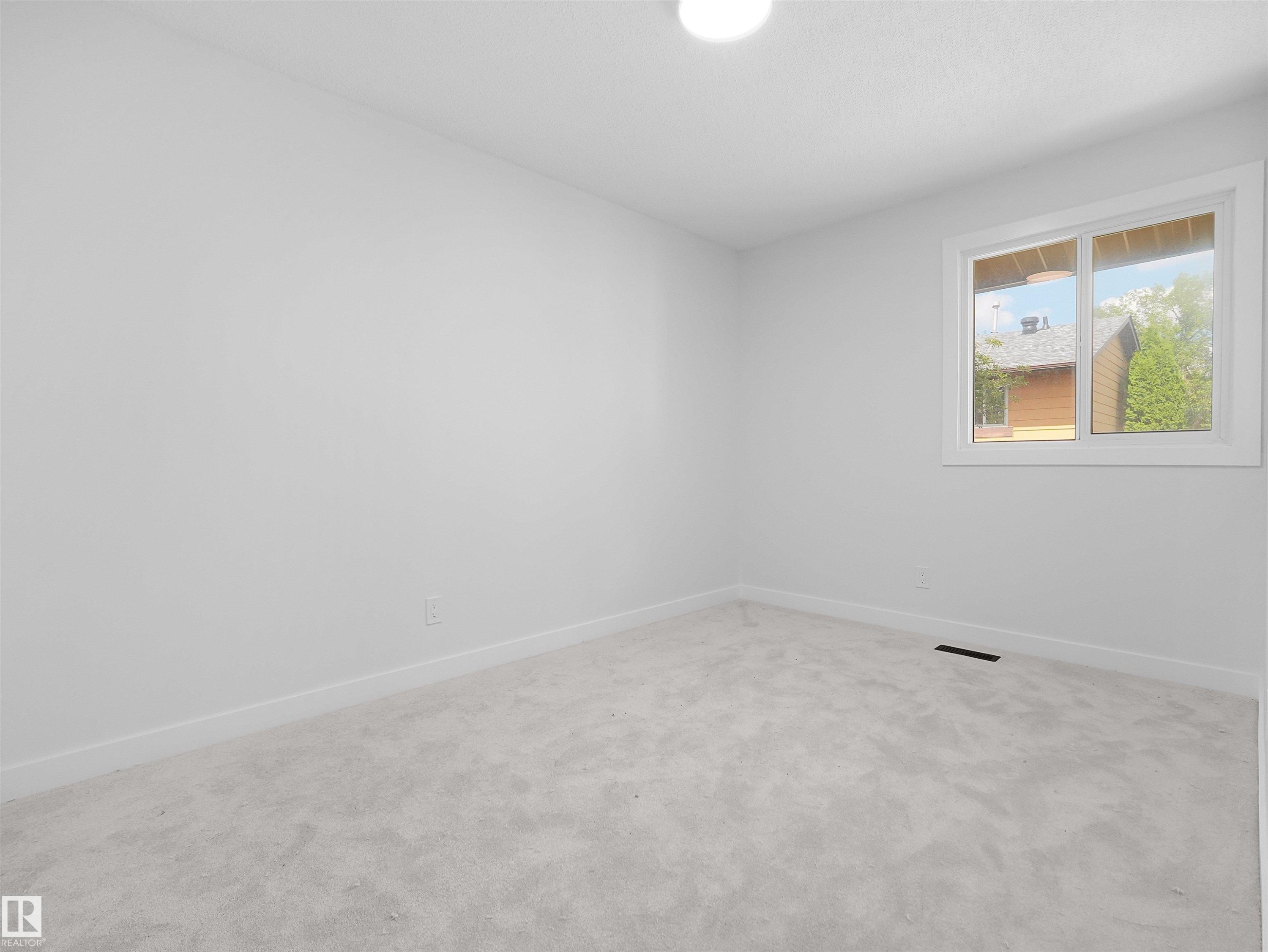White walls and light grey carpeting, featuring a single window with white trim, and a flush-mount ceiling light - 126 Woodstock Nw, Edmonton, AB - Indoor Photo Showing Other Room