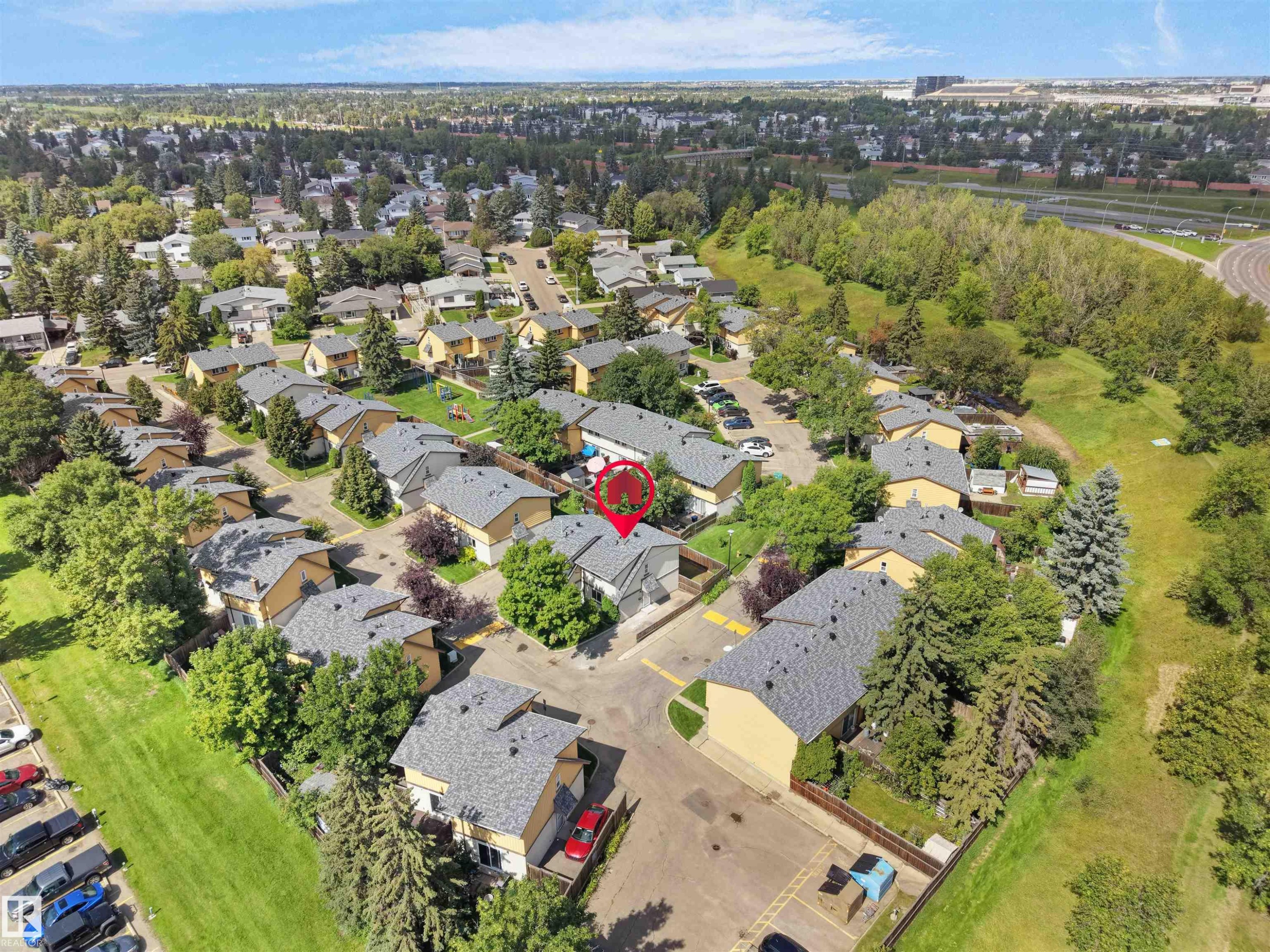 Residential community featuring multiple townhouse-style properties, mature trees, and paved roadways - 126 Woodstock Nw, Edmonton, AB - Outdoor With View