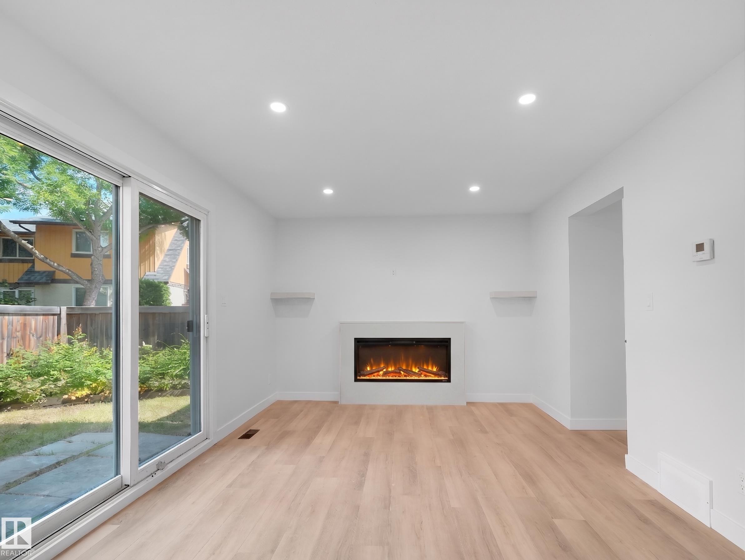 Recessed lighting illuminates wood-finish flooring - 126 Woodstock Nw, Edmonton, AB - Indoor With Fireplace