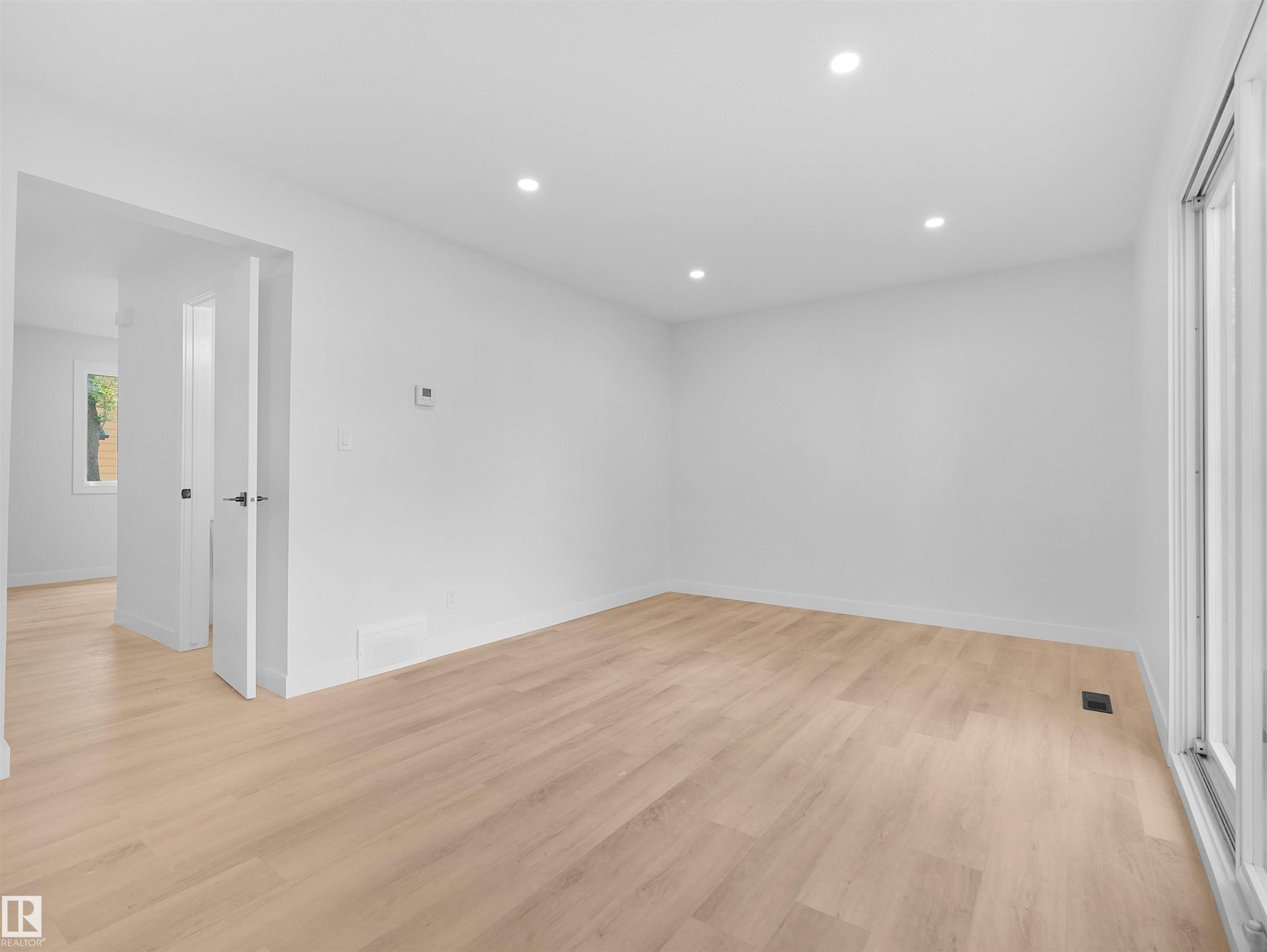 Recessed lighting, light wood-finish flooring, white walls, and a sliding glass door - 126 Woodstock Nw, Edmonton, AB - Indoor Photo Showing Other Room