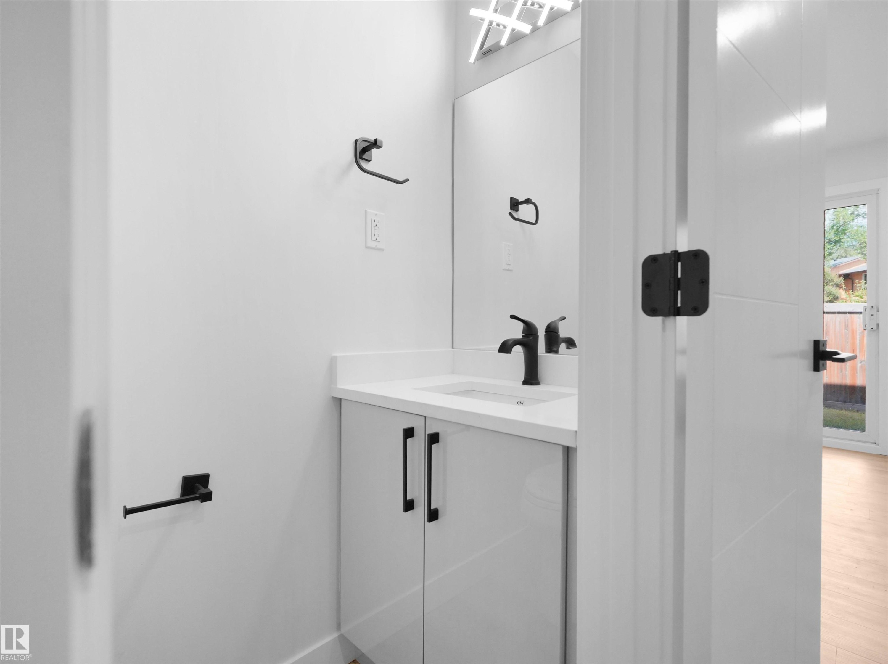Vanity with a white countertop and integrated sink, matte black faucet, and white cabinetry with black pulls - 126 Woodstock Nw, Edmonton, AB - Indoor Photo Showing Bathroom