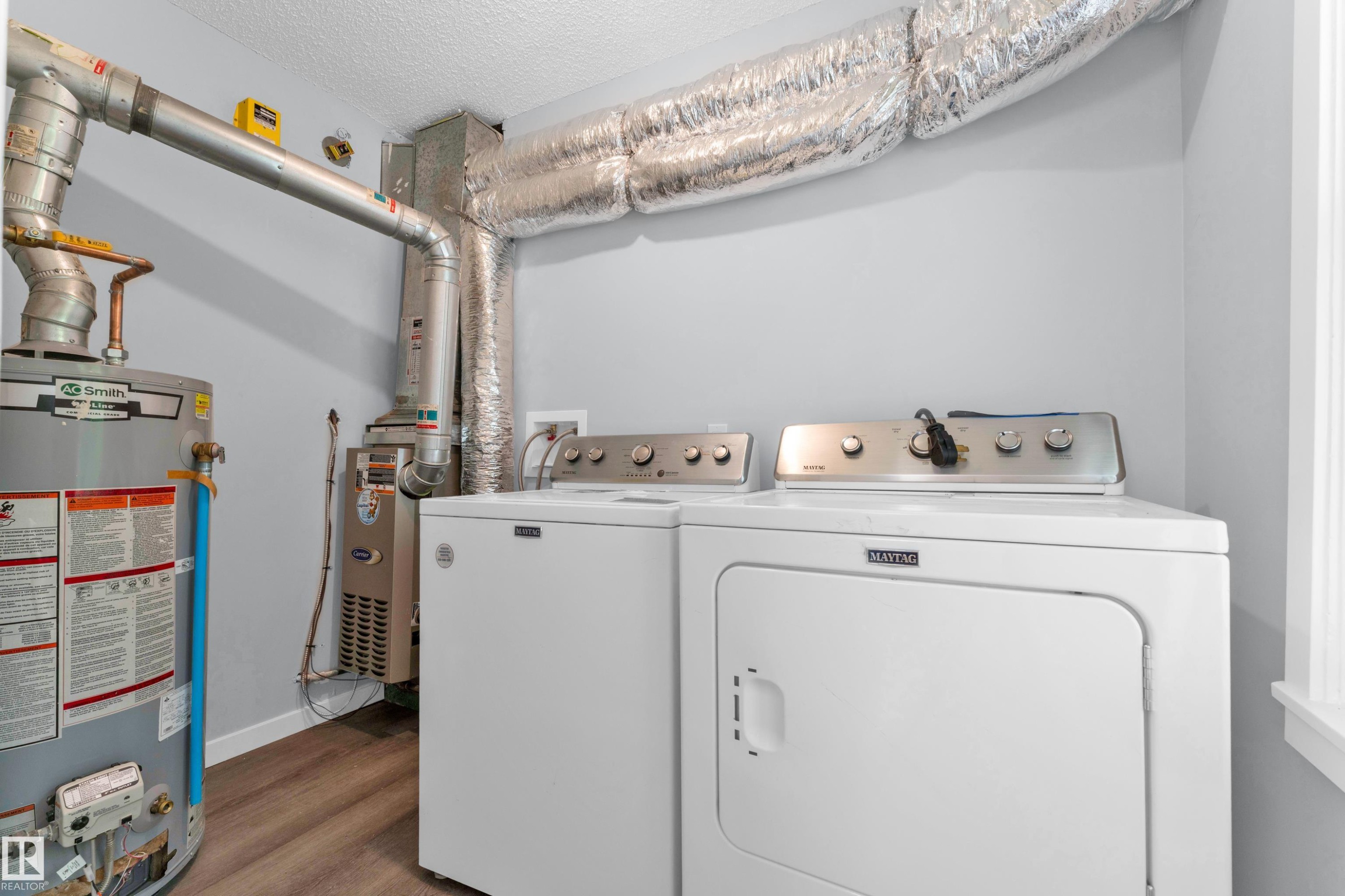 Dedicated utility area featuring a water heater, furnace, and wood-finish flooring - 9416 153 Street Nw, Edmonton, AB - Indoor Photo Showing Laundry Room