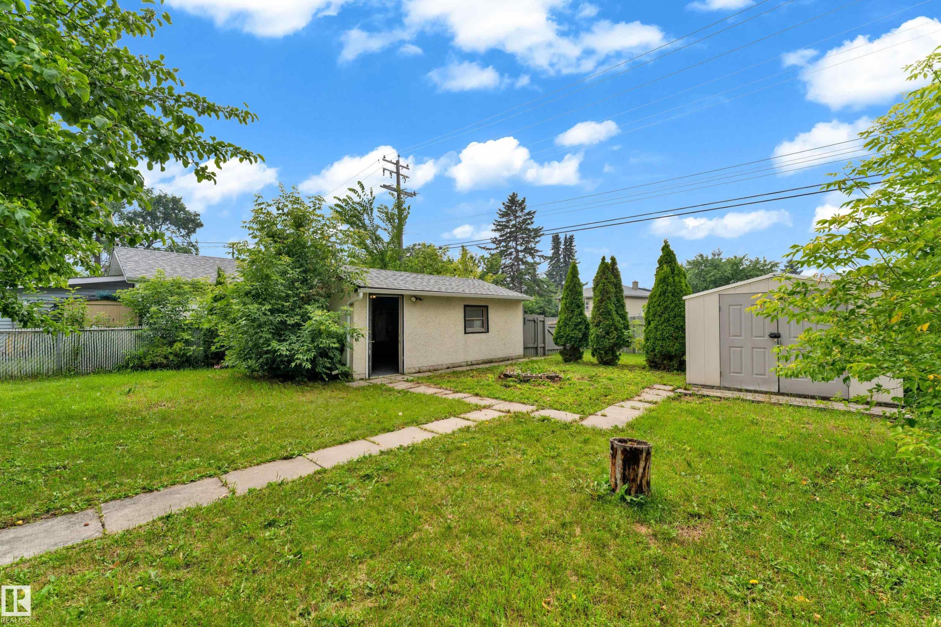 Expansive green space featuring a detached garage, a separate storage shed, concrete paver pathways, and mature trees - 9416 153 Street Nw, Edmonton, AB - Outdoor