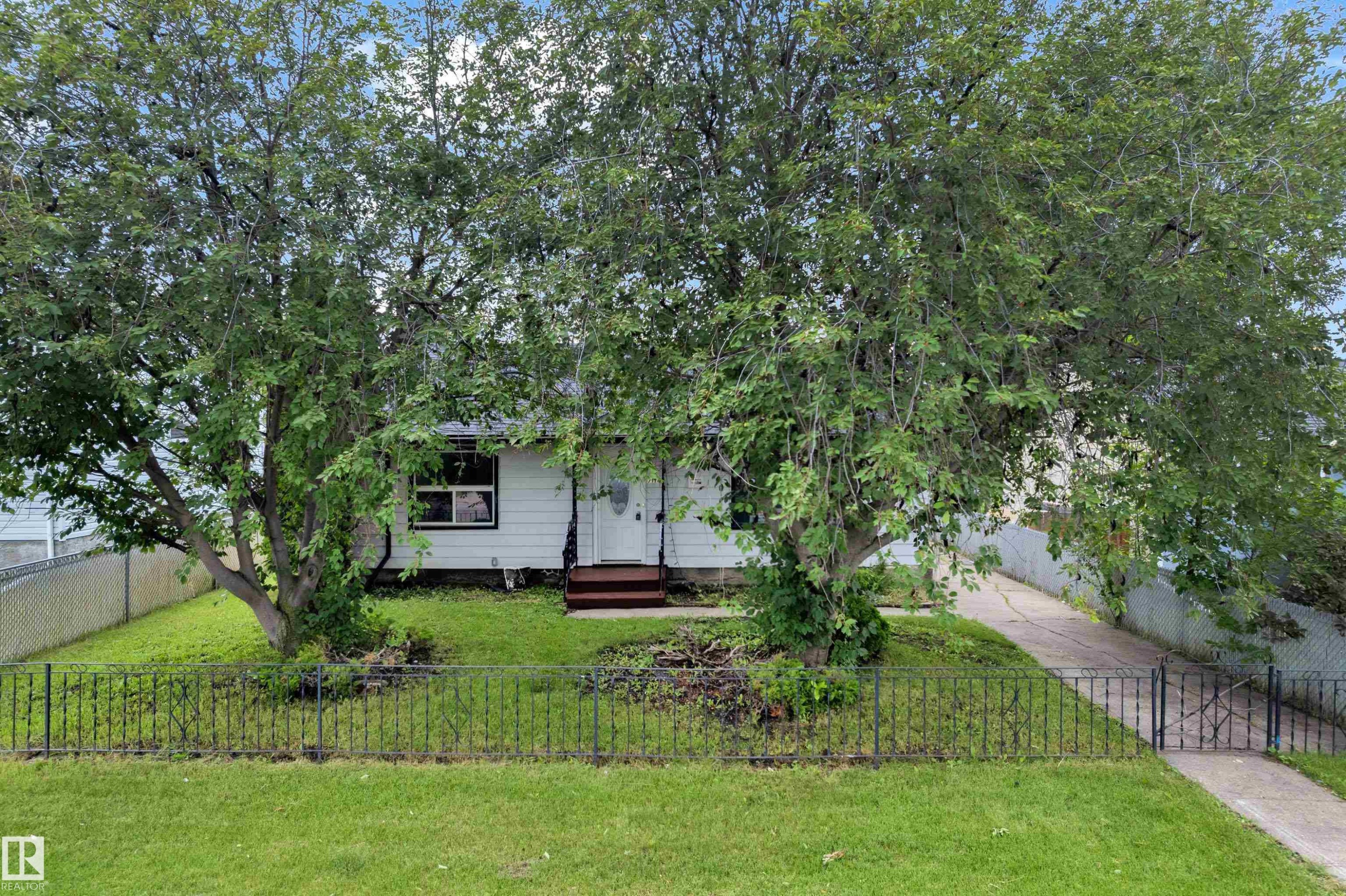 White-sided exterior with mature front yard trees providing natural shade - 9416 153 Street Nw, Edmonton, AB - Outdoor