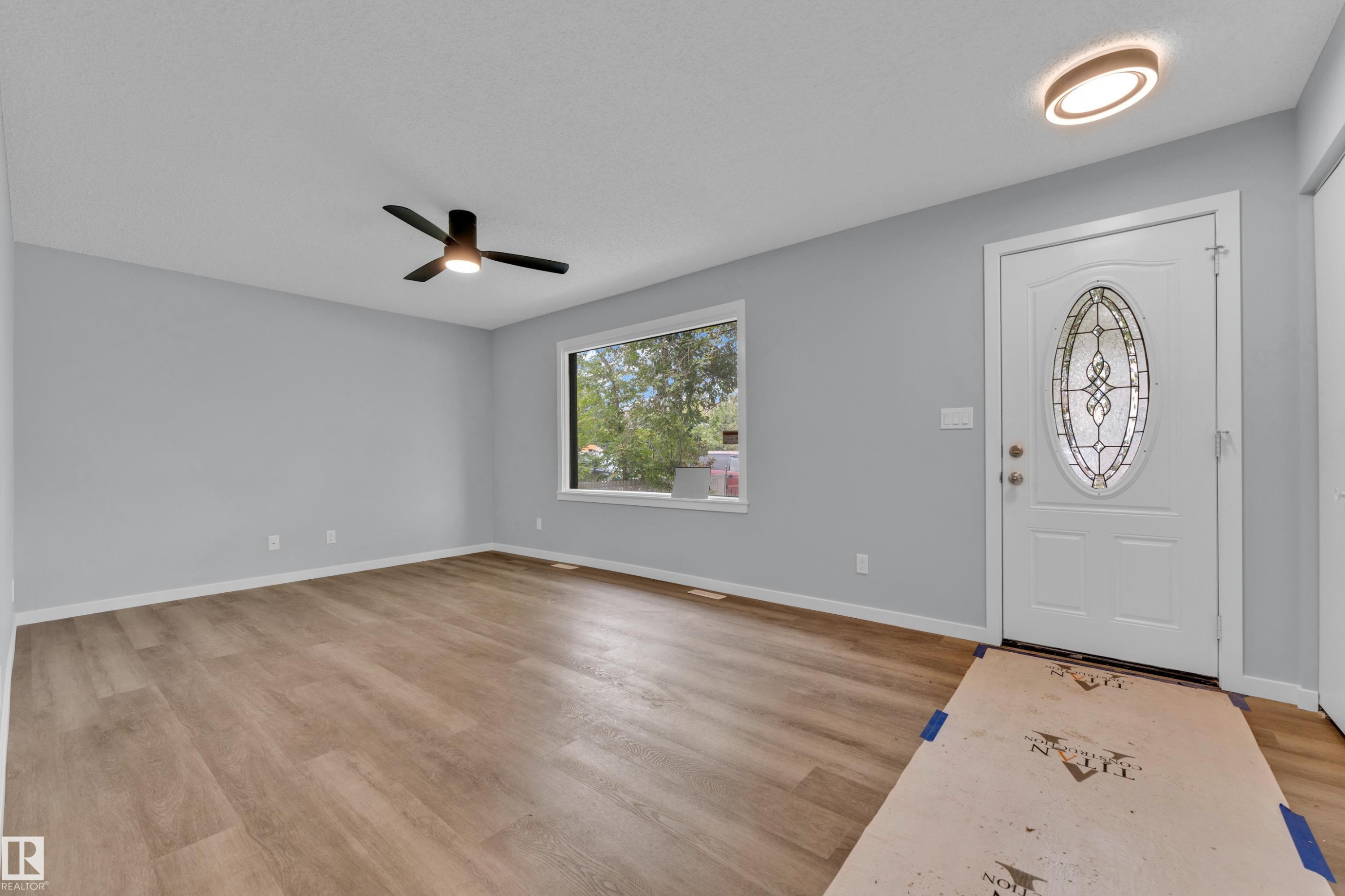 Entryway featuring wood-finish flooring, light gray walls, a white front door with an oval leaded glass insert, and a modern flush-mount light fixture - 9416 153 Street Nw, Edmonton, AB - Indoor Photo Showing Other Room