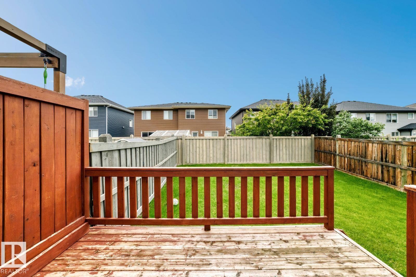 Deck with a wood railing and board fence overlooking a grass lawn - 1112 176 Street Sw, Edmonton, AB - Outdoor With Exterior