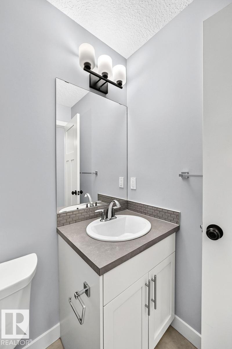 Vanity with a white shaker-style cabinet, a contemporary countertop, and an undermount sink - 1112 176 Street Sw, Edmonton, AB - Indoor Photo Showing Bathroom