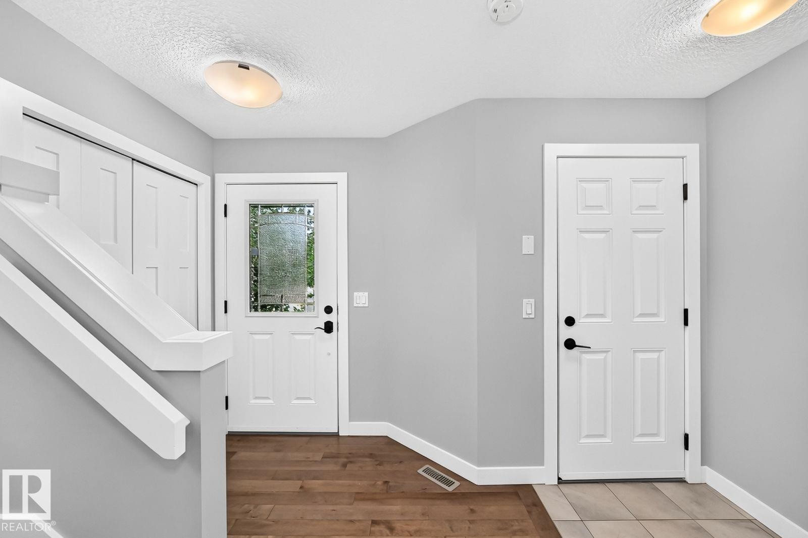 Entryway featuring a paneled door with decorative glass, wood-finish flooring, and white trim - 1112 176 Street Sw, Edmonton, AB - Indoor Photo Showing Other Room