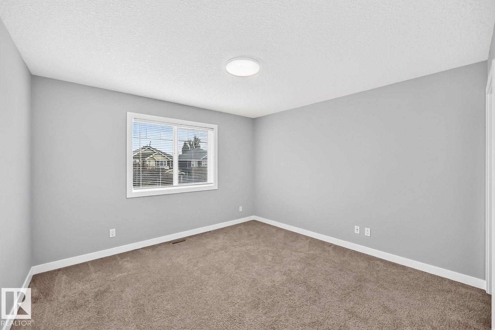 Neutral wall color palette, window with blinds, plush carpet flooring, white trim, and a ceiling-mounted light fixture - 1112 176 Street Sw, Edmonton, AB - Indoor Photo Showing Other Room