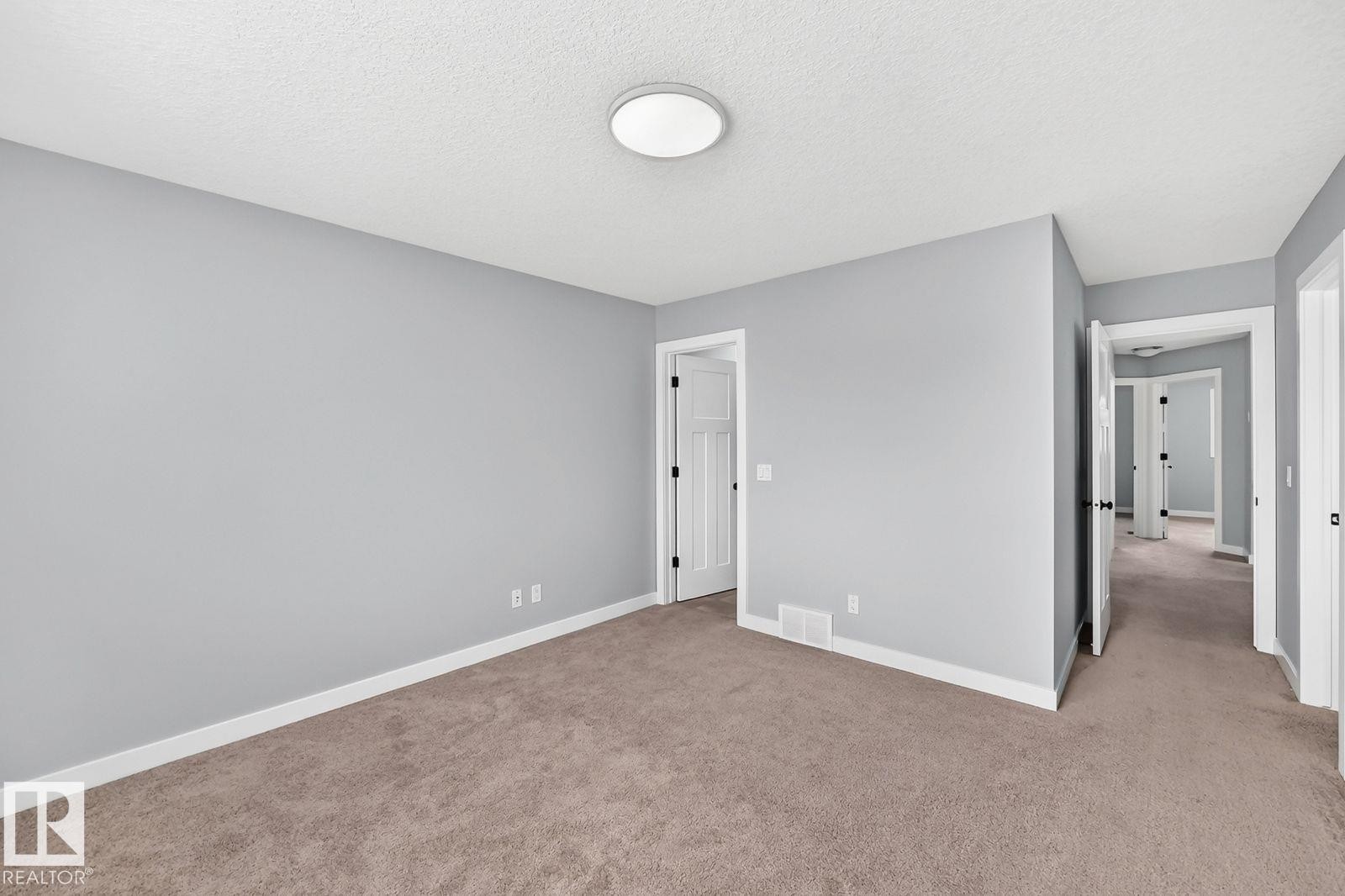 Neutral wall paint, textured ceiling, flush mount ceiling light, and plush carpet flooring - 1112 176 Street Sw, Edmonton, AB - Indoor Photo Showing Other Room