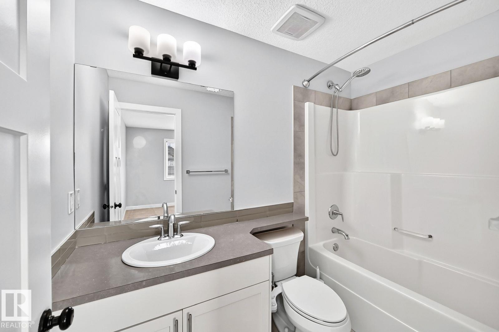 Bathroom featuring a single vanity with a white basin sink, polished chrome faucet, and gray countertop - 1112 176 Street Sw, Edmonton, AB - Indoor Photo Showing Bathroom