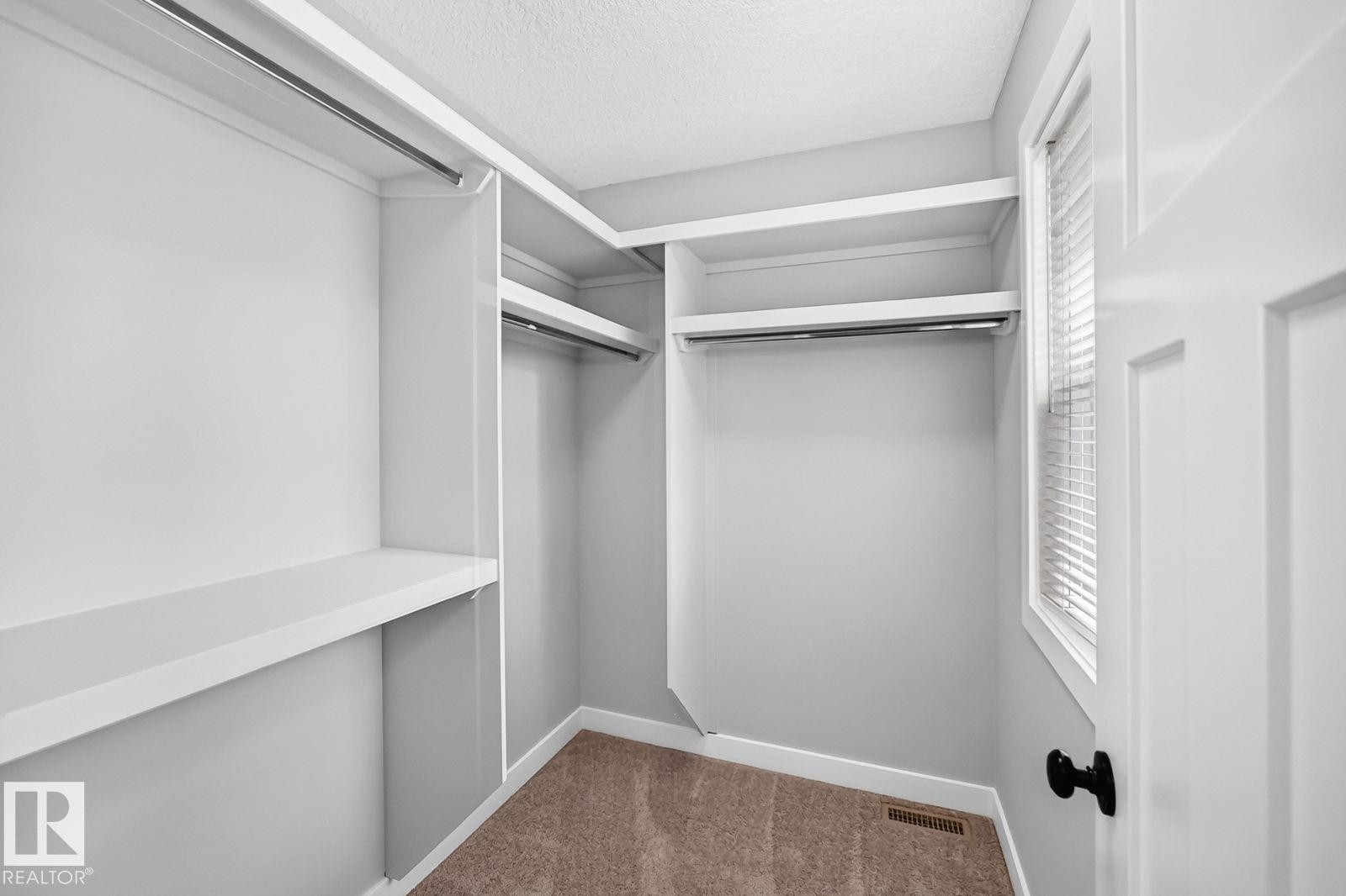 Walk-in closet featuring white built-in shelving, hanging rods, and a window with blinds - 1112 176 Street Sw, Edmonton, AB - Indoor With Storage