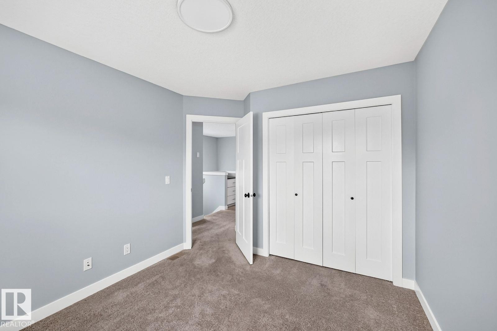 Carpeted flooring, light blue wall paint, white trim, white bi-fold closet doors, and a ceiling-mounted light fixture - 1112 176 Street Sw, Edmonton, AB - Indoor