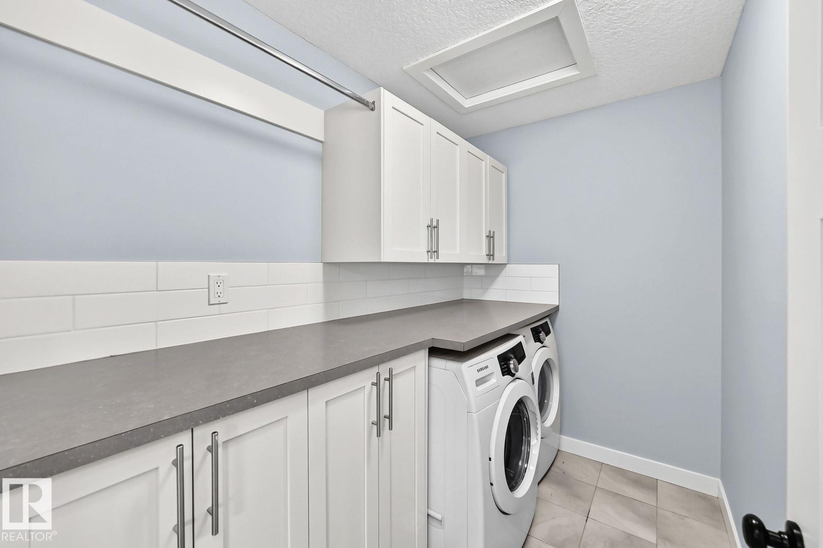 White shaker cabinetry, gray countertops, white subway tile backsplash, and light-toned tile flooring - 1112 176 Street Sw, Edmonton, AB - Indoor Photo Showing Laundry Room