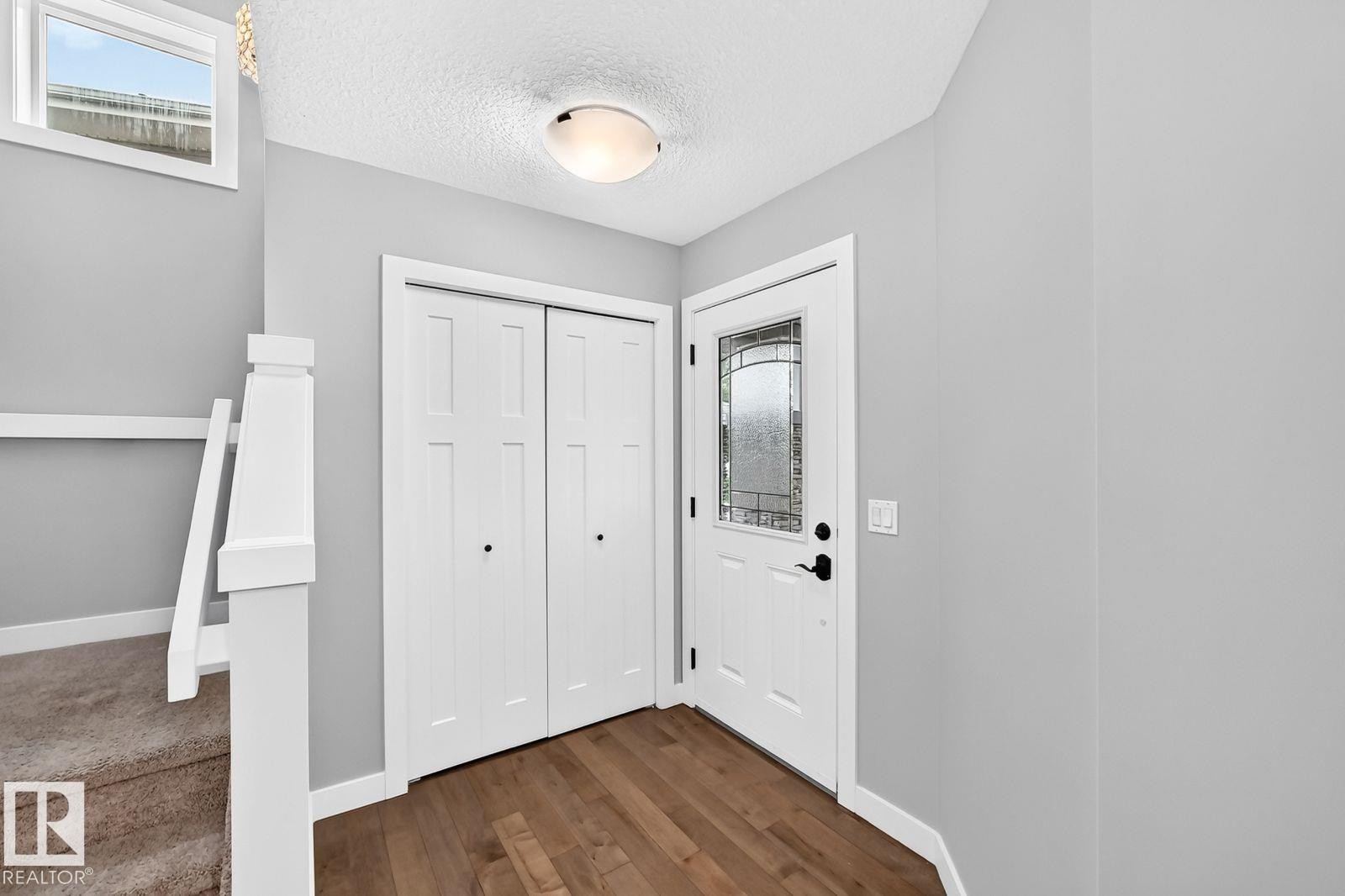 Entryway featuring wood-finish flooring and a white front door with decorative glass - 1112 176 Street Sw, Edmonton, AB - Indoor Photo Showing Other Room