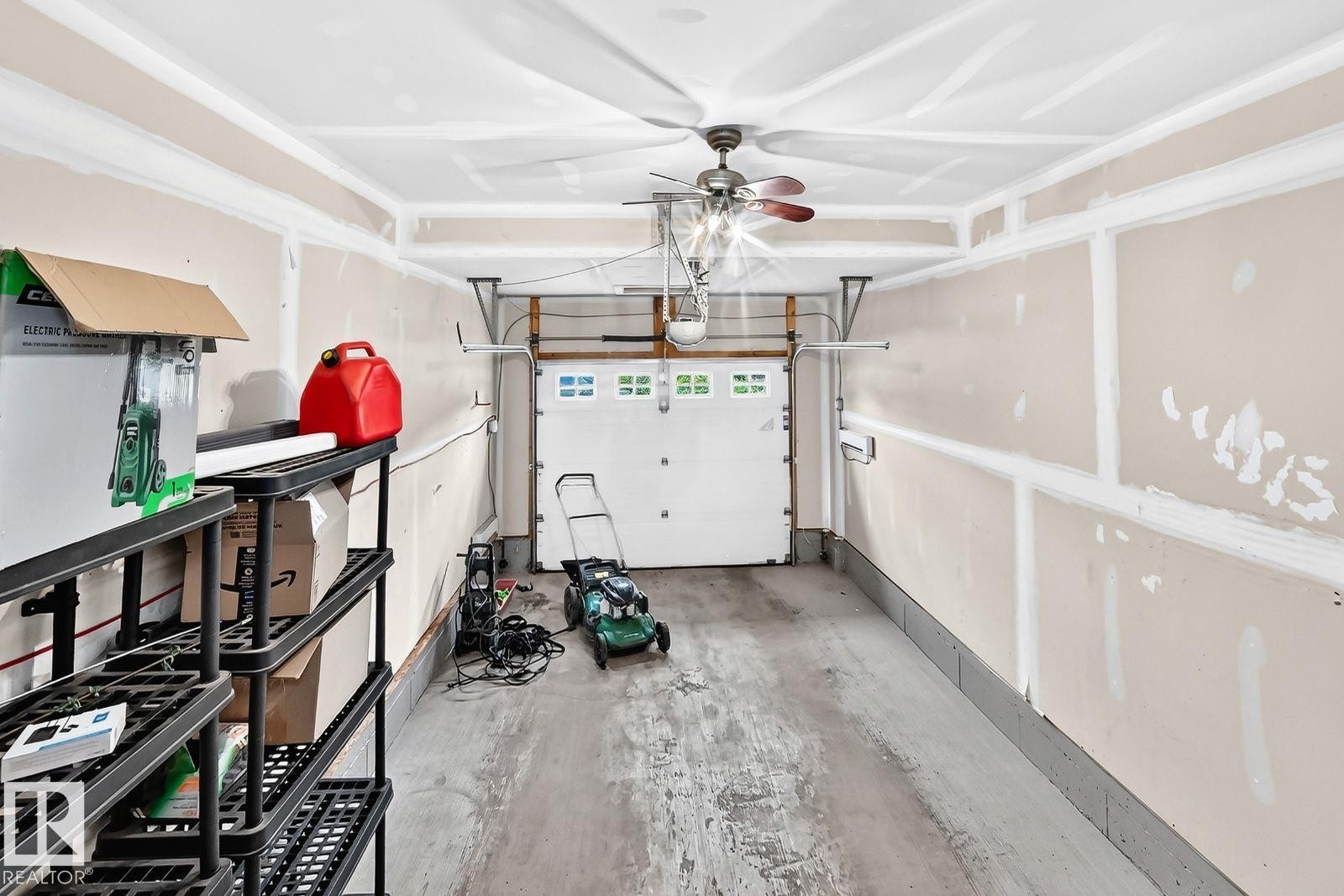 Attached garage with a roll-up door, equipped with a ceiling fan, and concrete flooring - 1112 176 Street Sw, Edmonton, AB - Indoor Photo Showing Garage