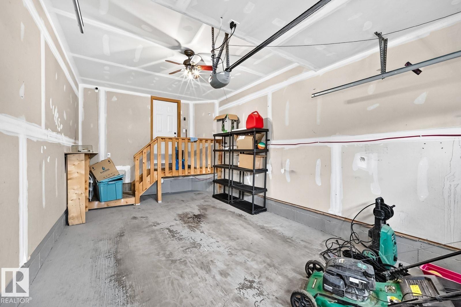 Garage with concrete flooring, exposed wall studs, and a ceiling fan - 1112 176 Street Sw, Edmonton, AB - Indoor Photo Showing Garage
