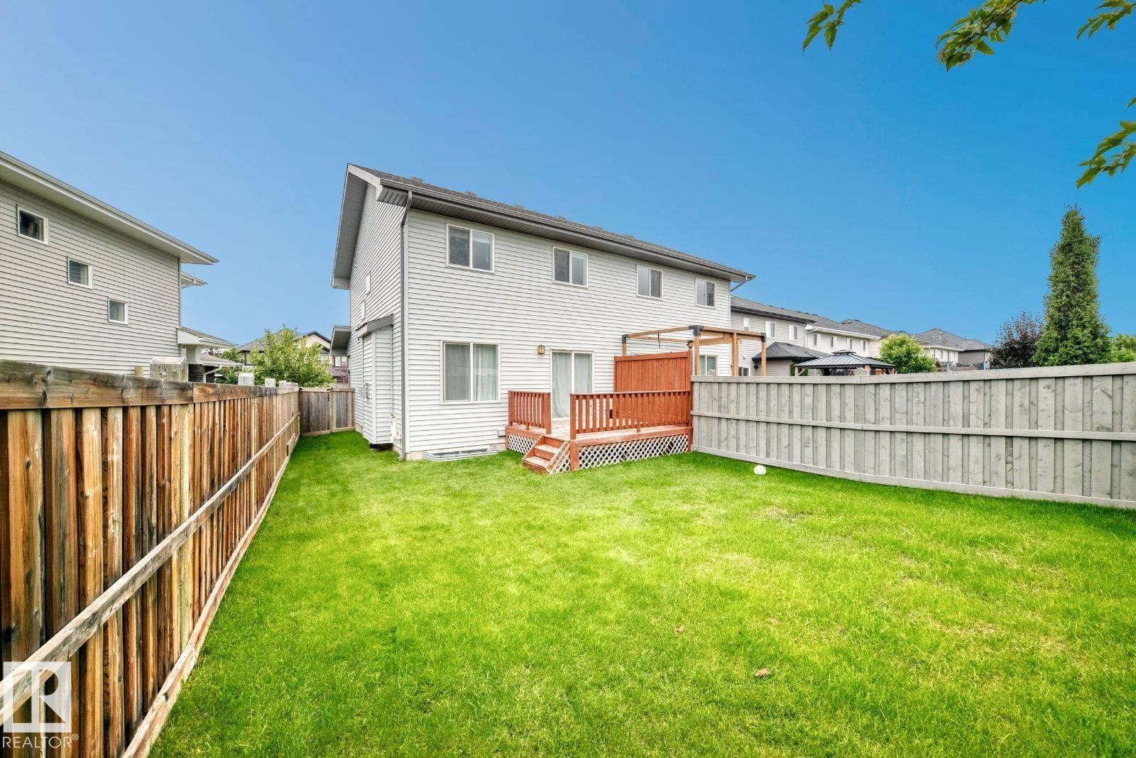 Expansive fenced backyard featuring a manicured lawn, multi-level wood deck, and wood pergola - 1112 176 Street Sw, Edmonton, AB - Outdoor With Exterior